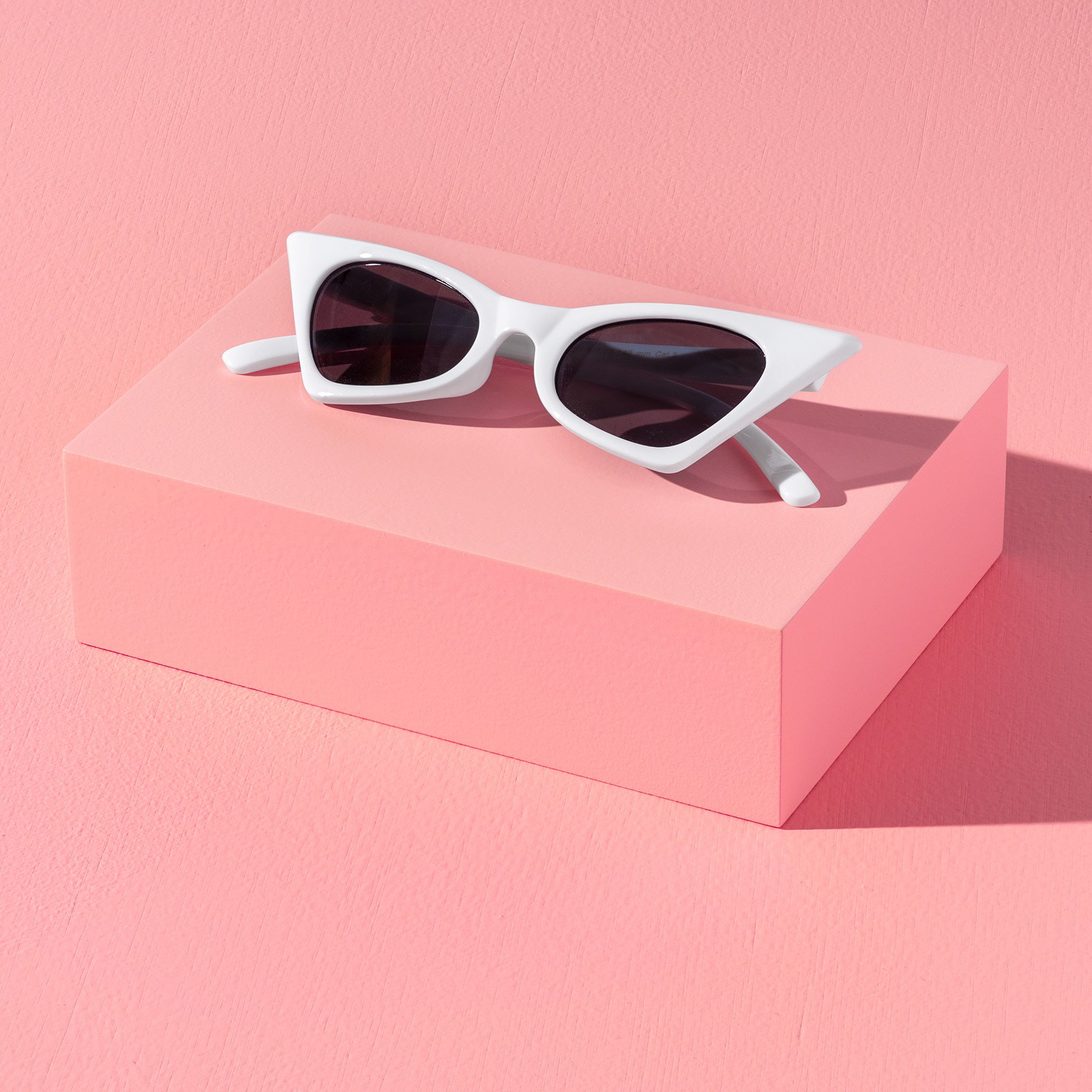 One rectangular pink product photography box displaying a pair of white sunglasses