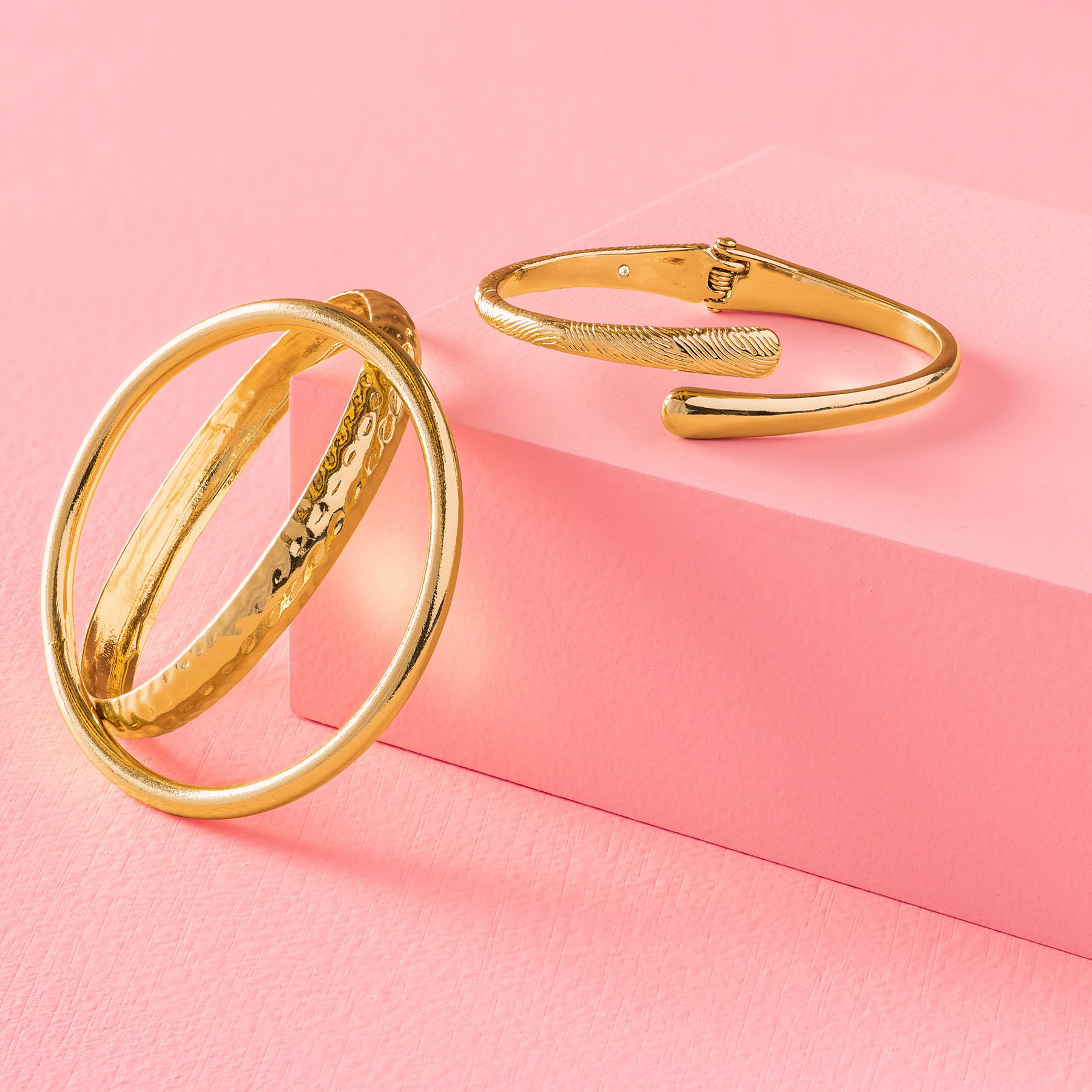 One rectangular pink product photography riser displaying gold bangles