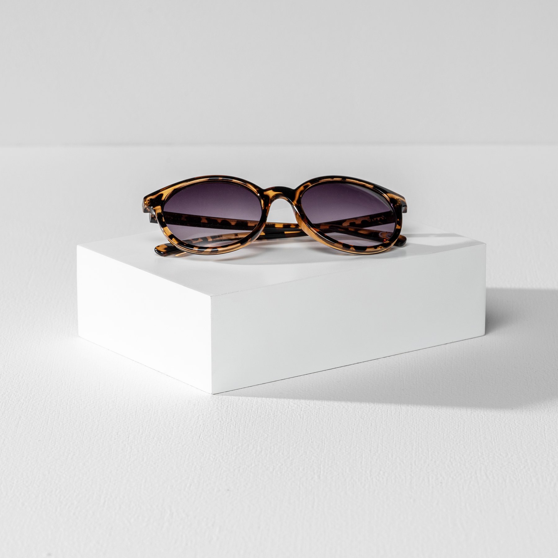 One rectangular white product photography riser displaying a pair of sunglasses