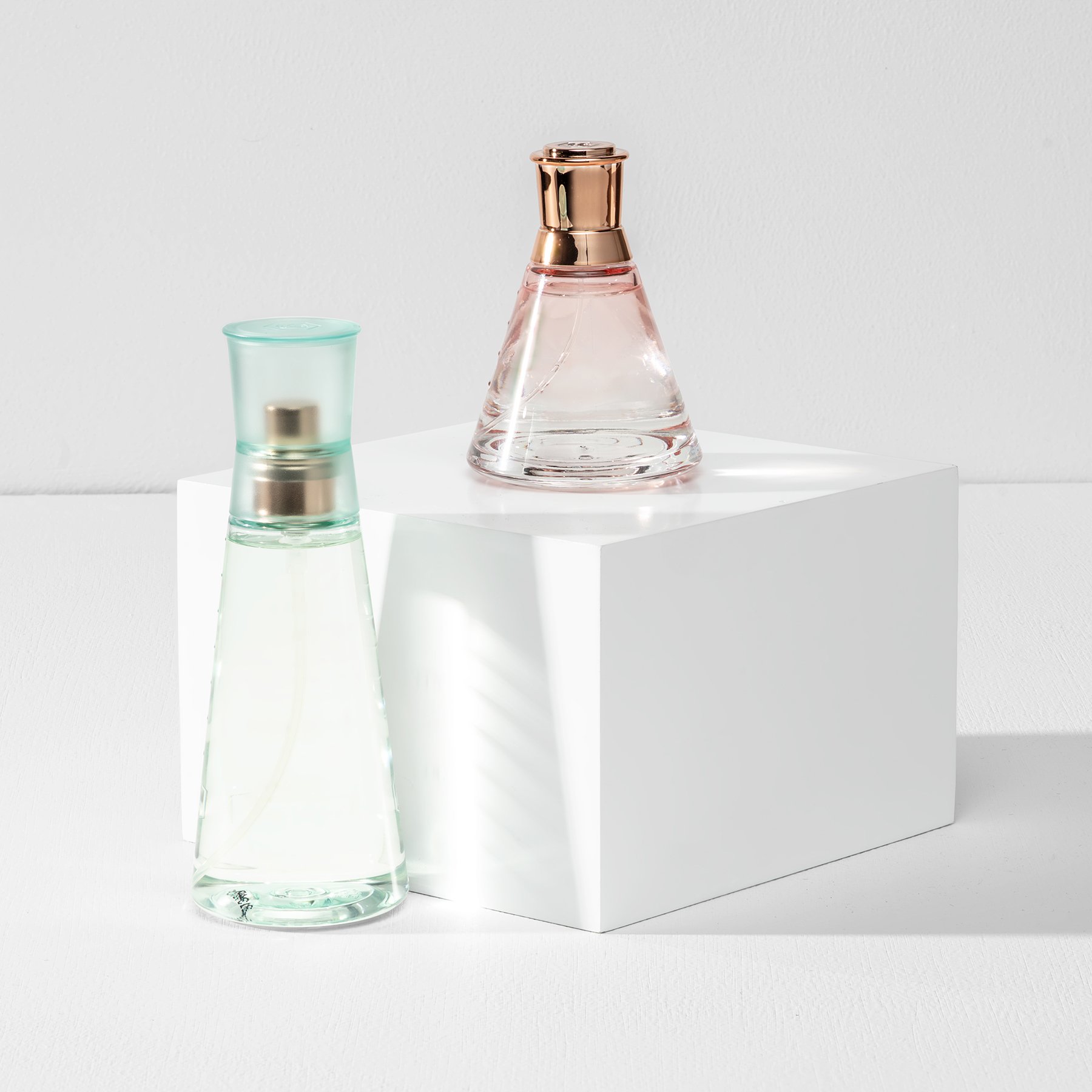 White product photography box displaying pink and green perfume bottles