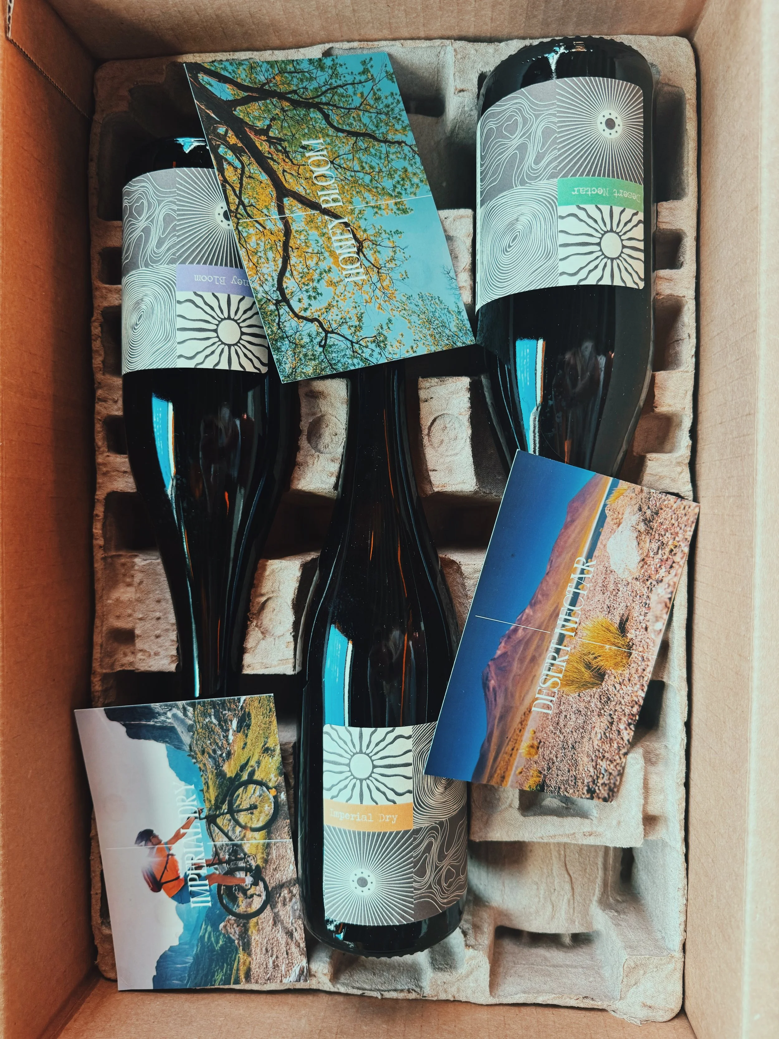 Hand holding a Saro whiskey barrel aged sour cherry beverage bottle in front of a large wooden barrel labeled "World Cooperage".