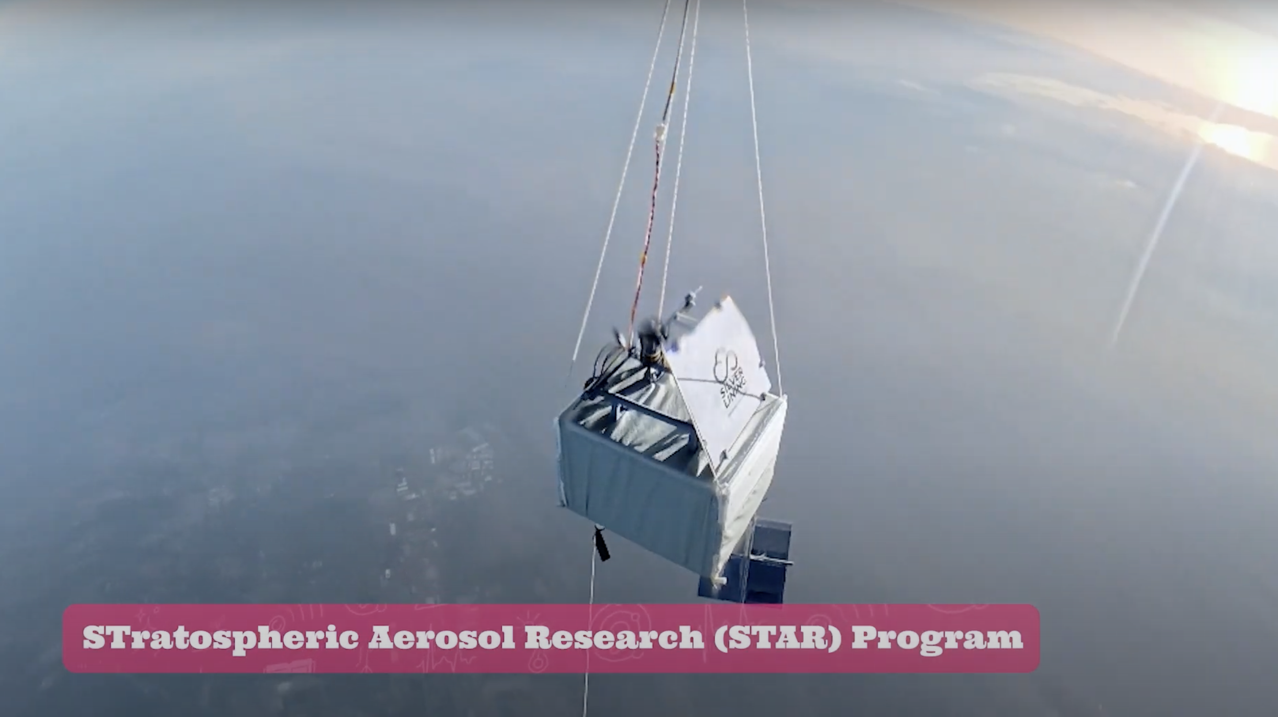 A satellite or scientific instrument suspended in the sky over a body of water, associated with the Stratospheric Aerosol Research (STAR) Program.