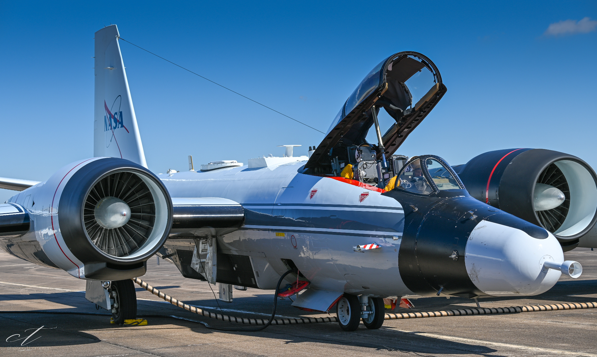 A NASA experimental jet aircraft with open cockpit, parked on tarmac under a clear blue sky.