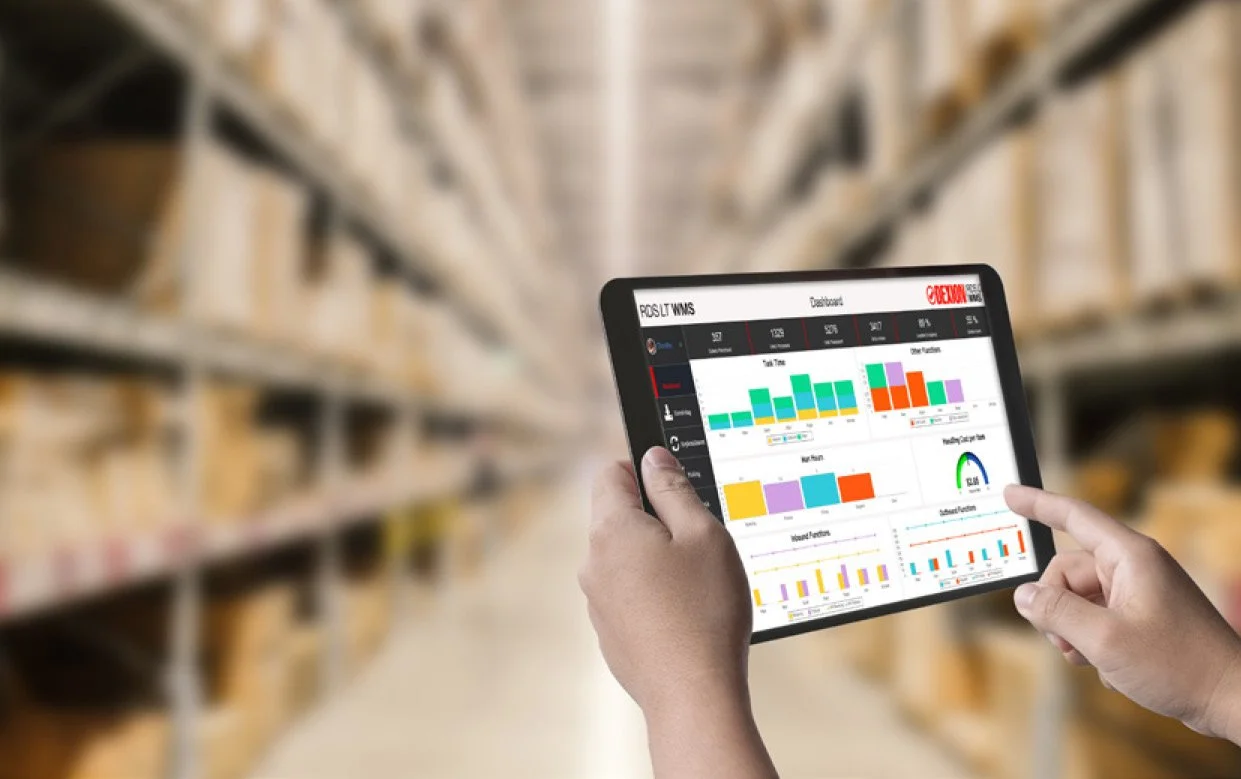 Person holding a tablet displaying analytics data in a warehouse aisle with shelves