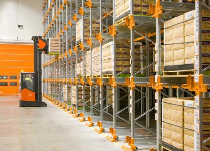 Panoramic view of high-density automated warehouse storage system featuring orange shuttle carriers and multiple levels of pallet racking for optimized inventory management