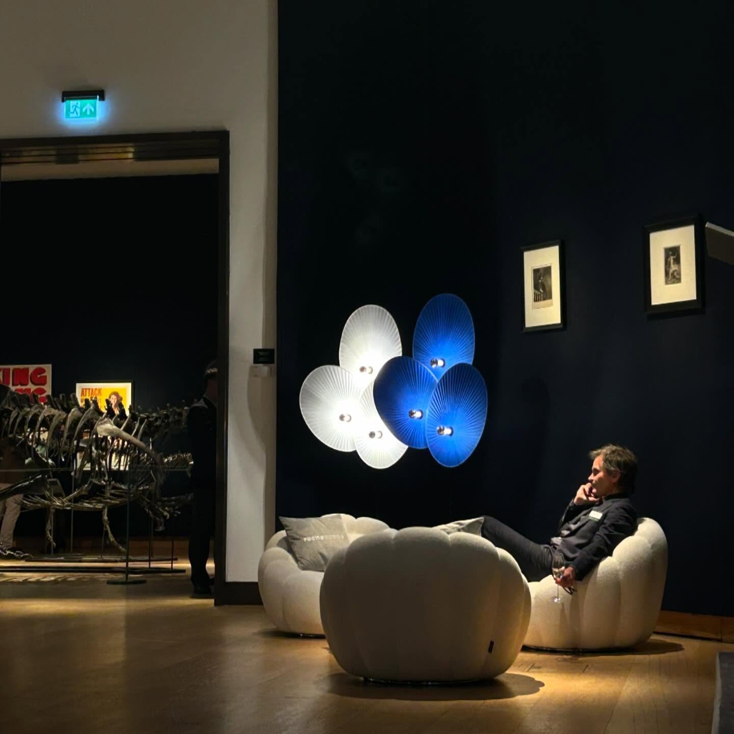 A guest just casually drinking a glass of champagne on a @rochebobois armchair with a stegosaurus in the background