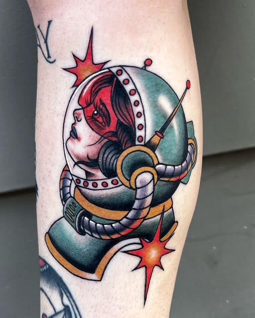 Tattoo of a woman inside a spaceship helmet with a retro style, featuring explosions and a tattoo of a star in the background.