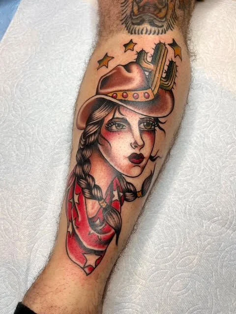 Tattoo of a woman with braided hair, wearing a cowboy hat and a red shirt, with stars above her head.