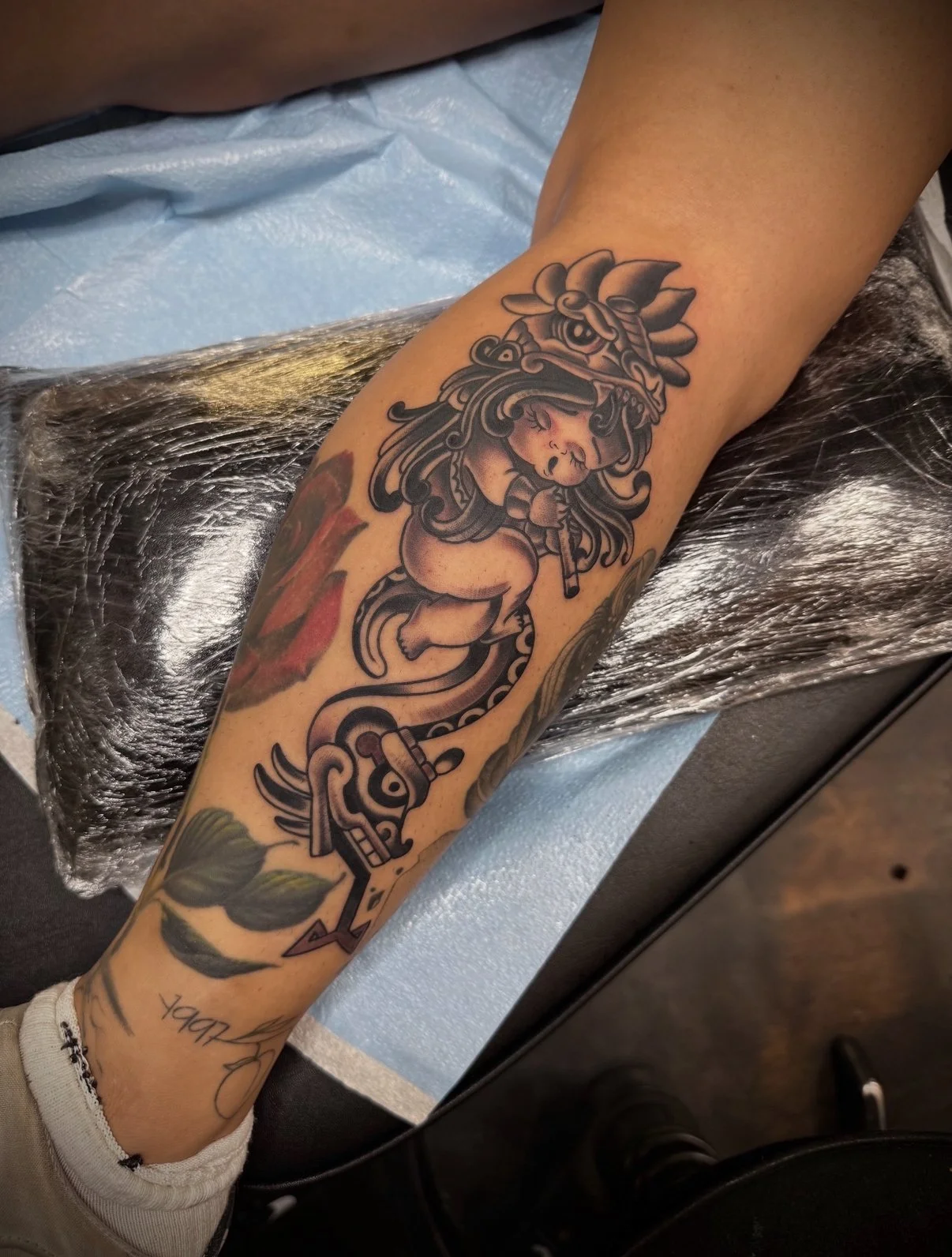Tattoo of a stylized lion head with a floral design, on a person's forearm.