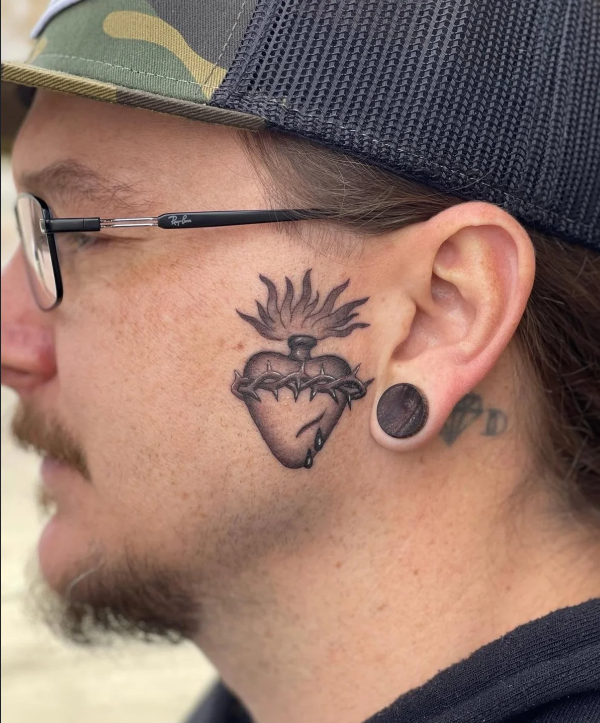 Tattoo of an anatomical heart with flames on the shoulder.