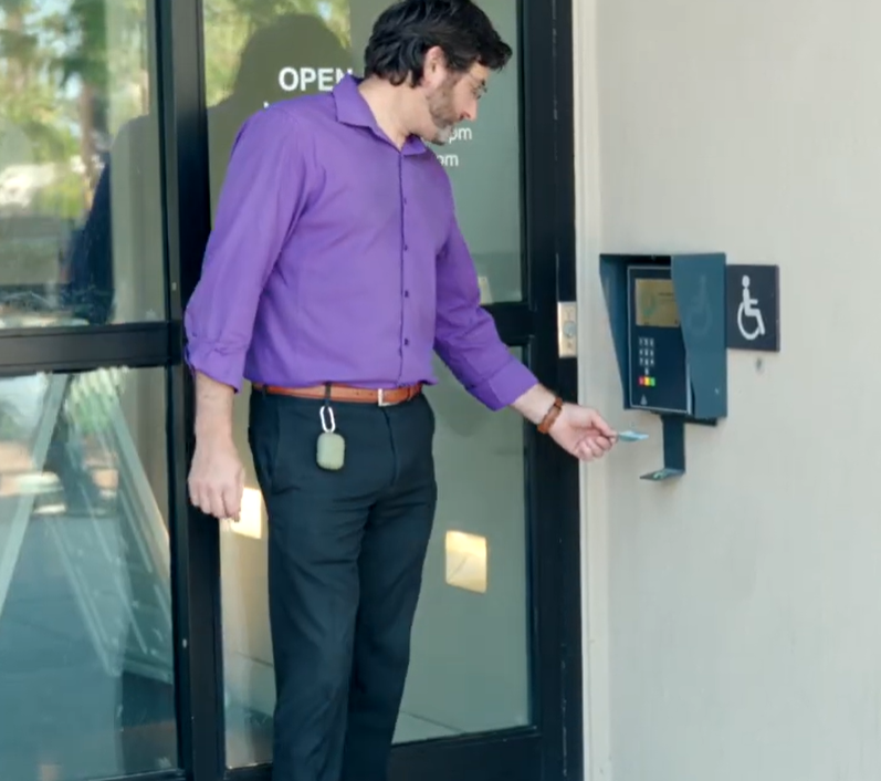 Person using a card reader at a library entrance to unlock the door, demonstrating accessible, self-service library entry.