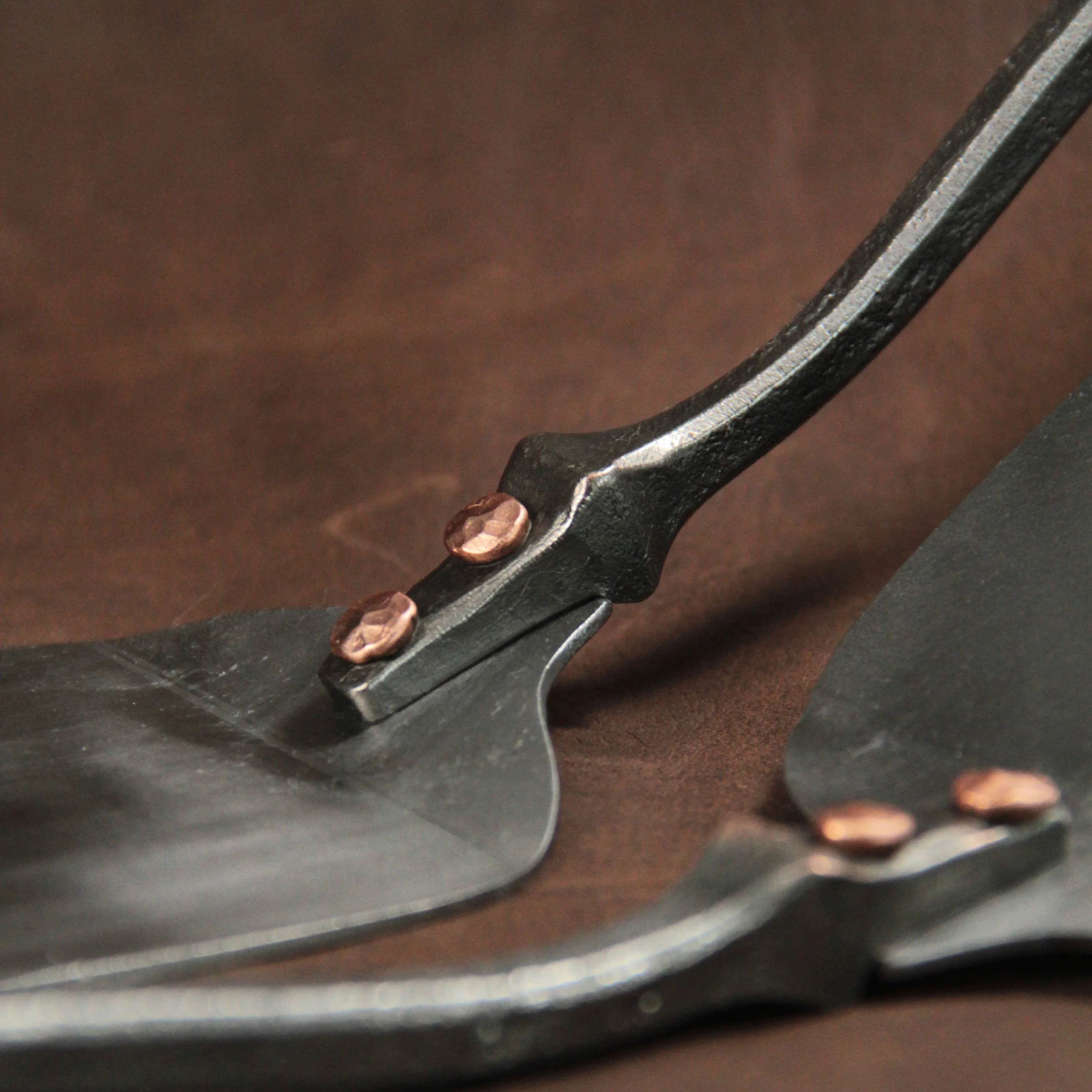 A railroad spike spatula with copper rivets holding on the stainless steel blade