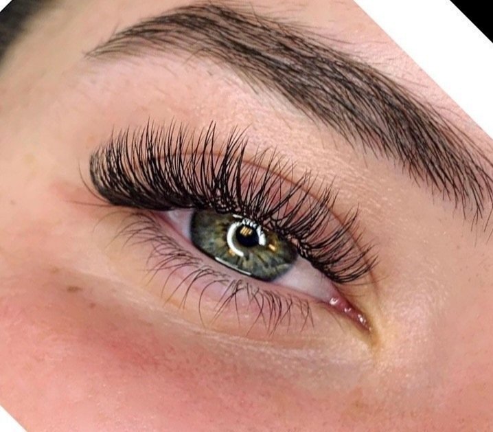 Close-up of a person's eye with long, curled eyelashes and a well-groomed eyebrow.