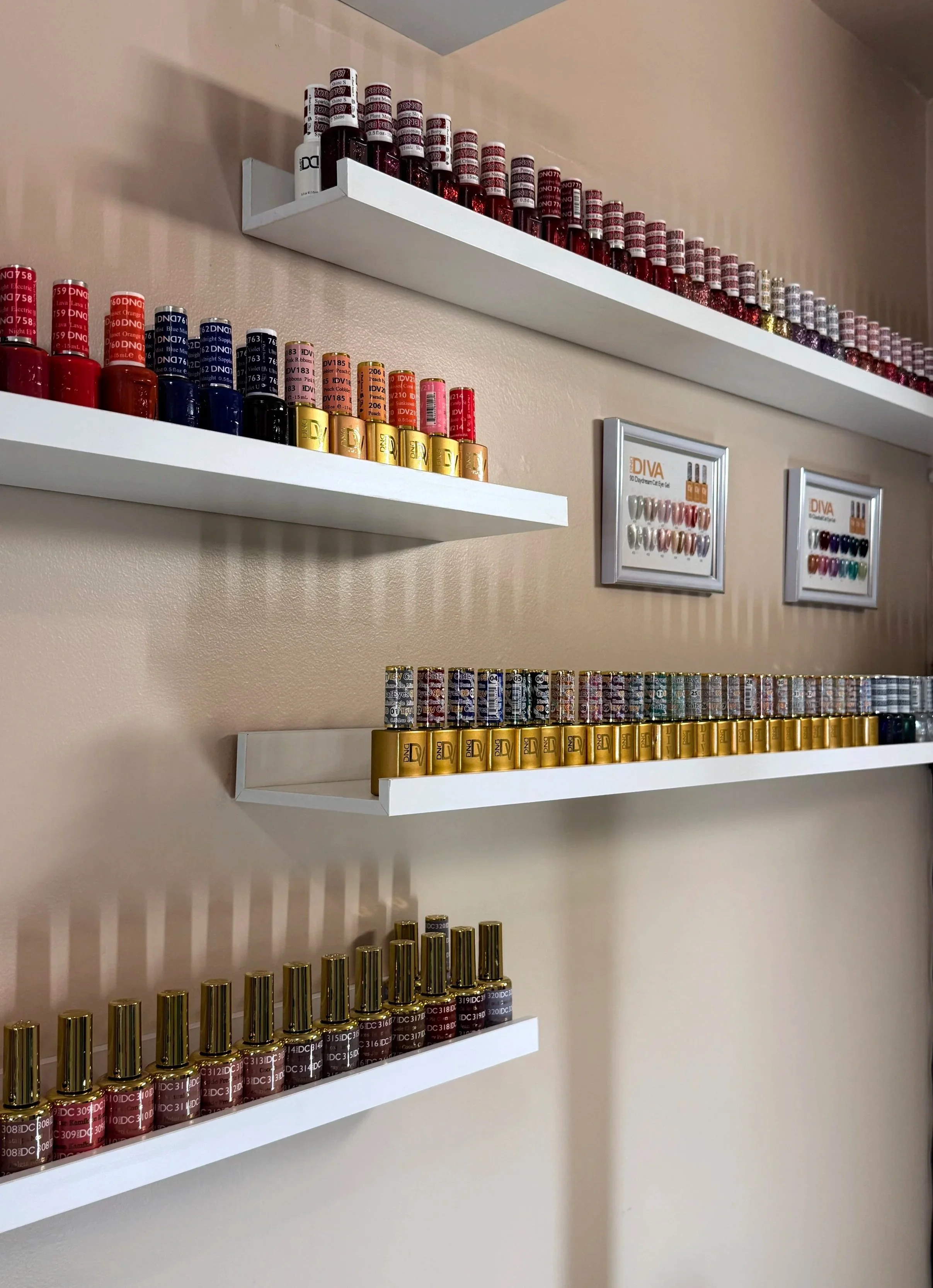 Multiple shelves with various bottles of nail polish in different colors arranged in rows on beige walls.