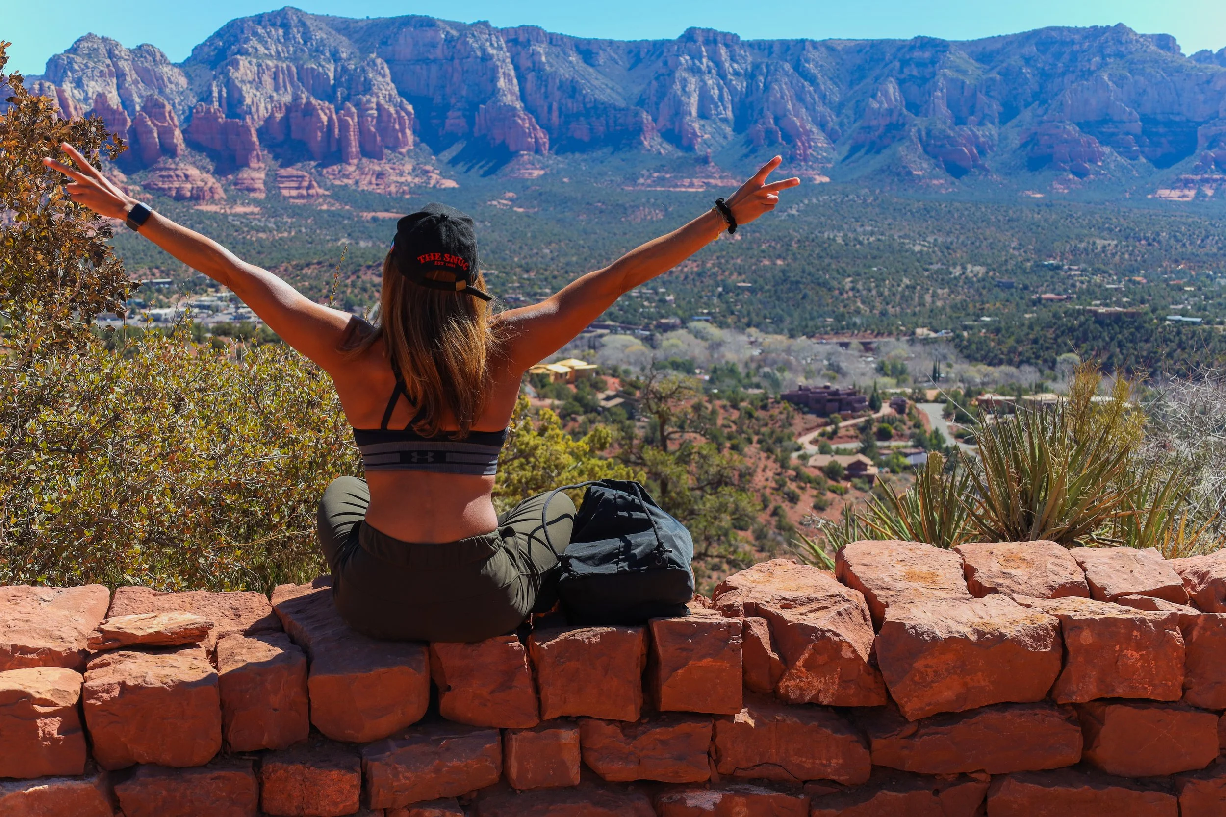 Young woman with her arms raised looking out into the mountains of Arizona