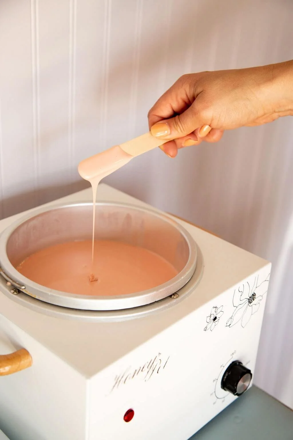 Aesthetician dipping a stick into wax