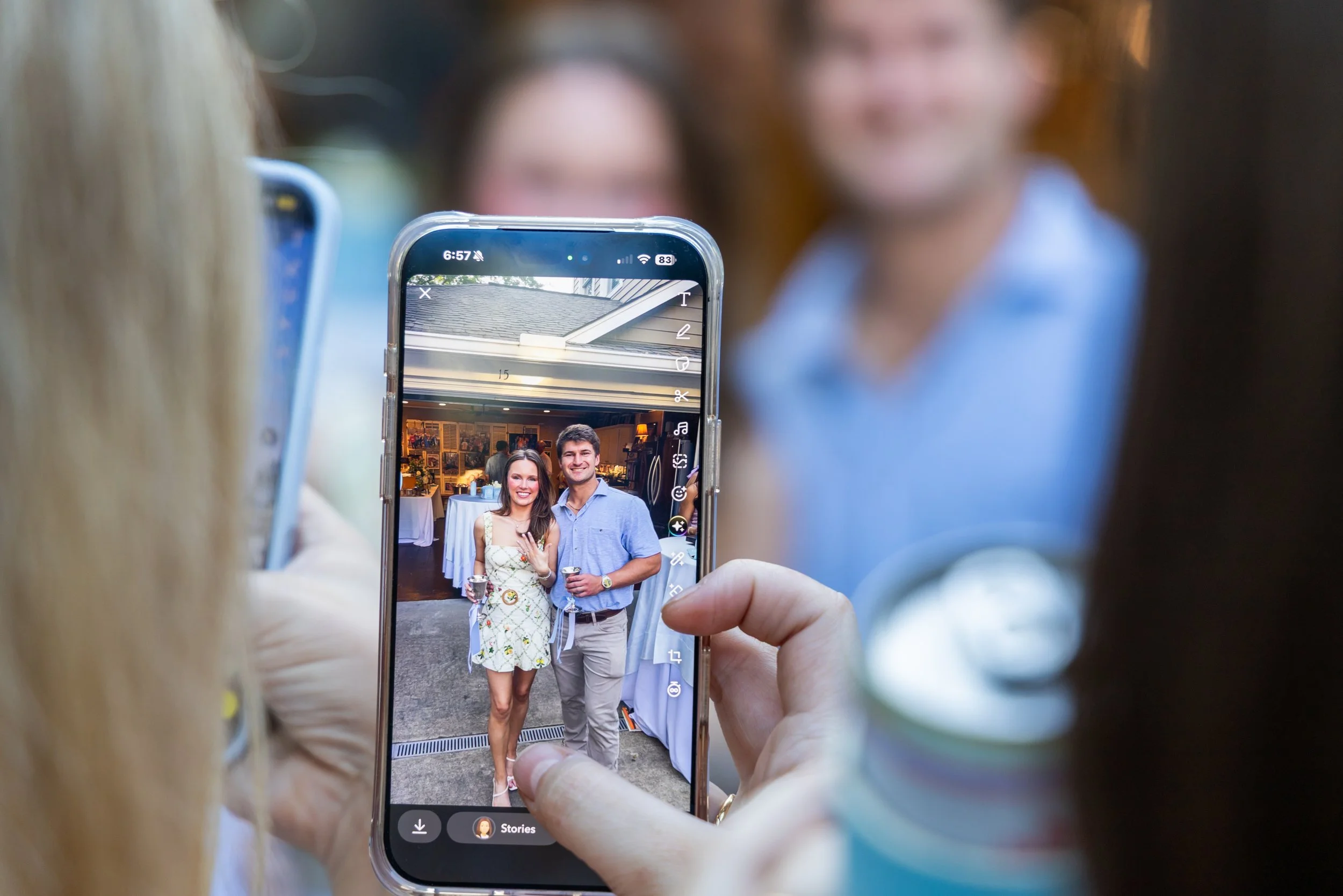 Friends taking pictures on their phone of a newly engaged couple at an engagement party in Oxford, MS on May 9, 2026.
