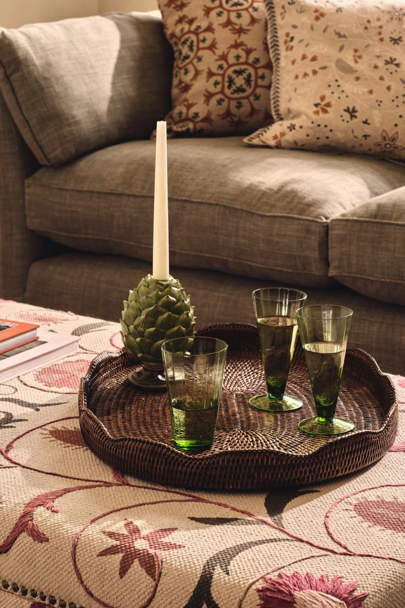 brown woven tray with glasses and a green candle holder