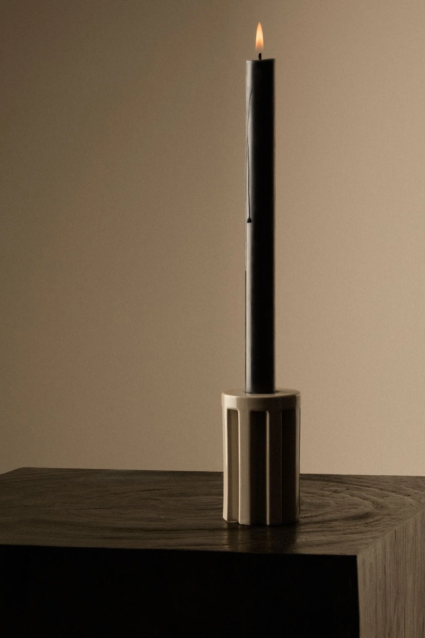 Kelly Hoppen x M&S candleholder with a tall black taper candle on a dark wooden surface.