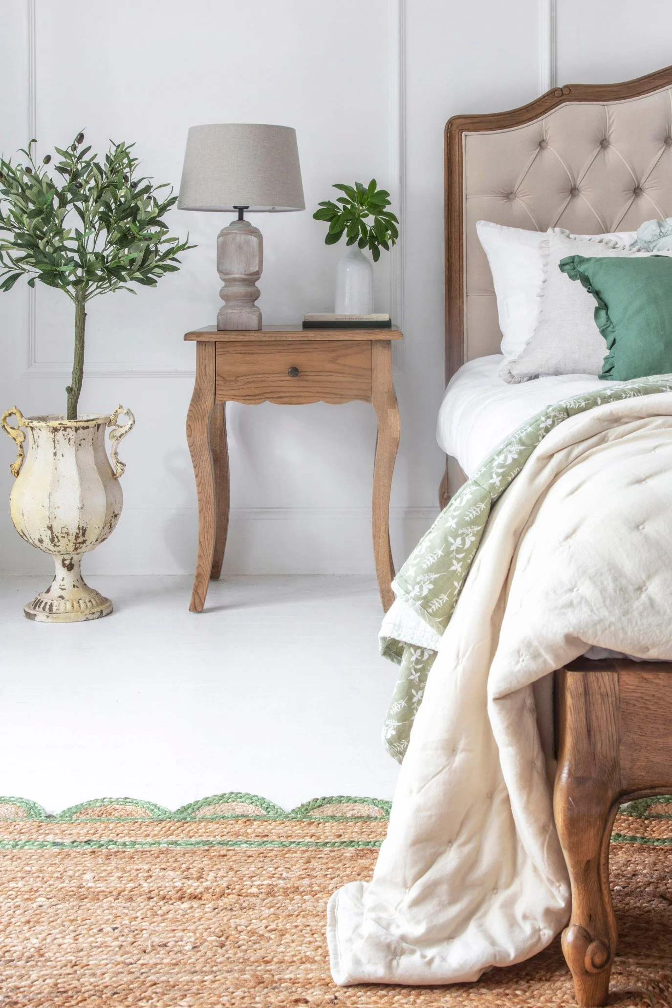 Tall French-style oak nightstand with tapered legs and stone lamp in an elegant white bedroom