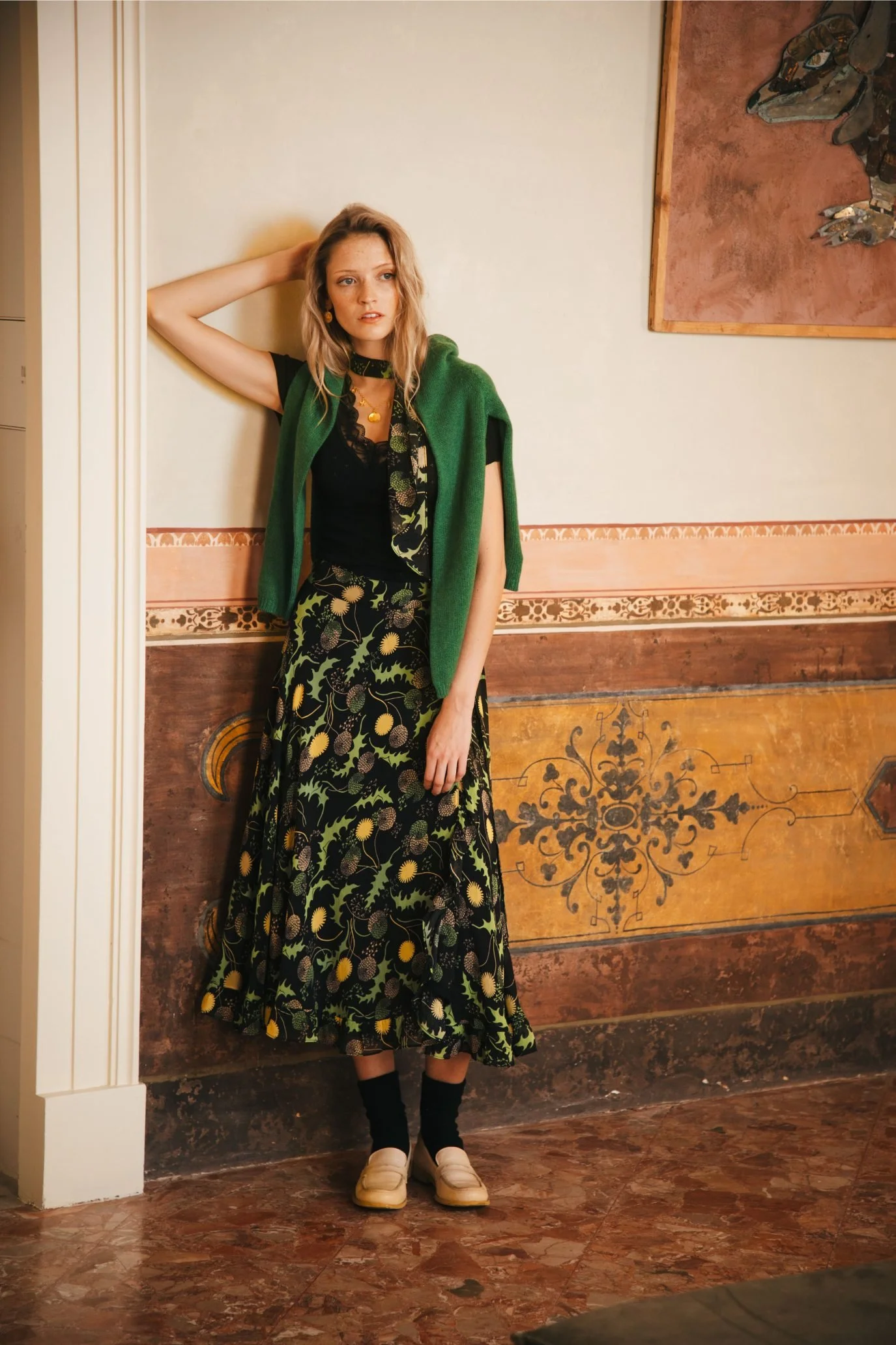A model wearing a green printed dress in a vintage style room