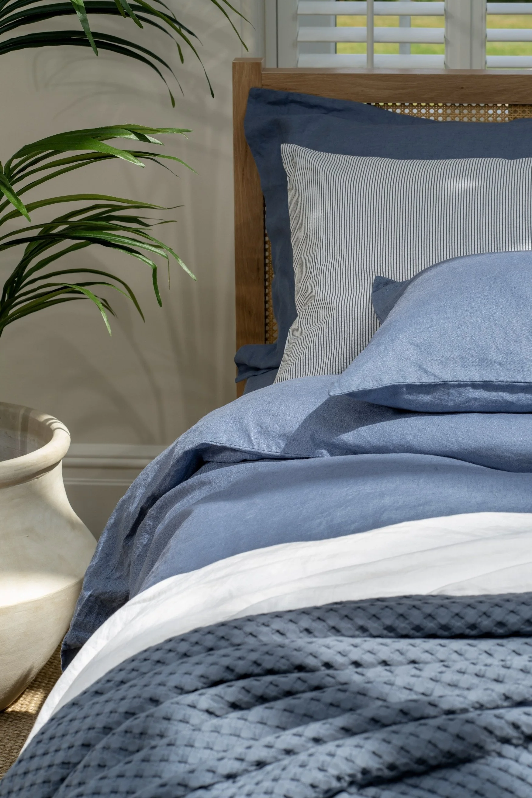 A bed with blue duvet and pillows teamed with a blue throw and a fine blue striped pillow