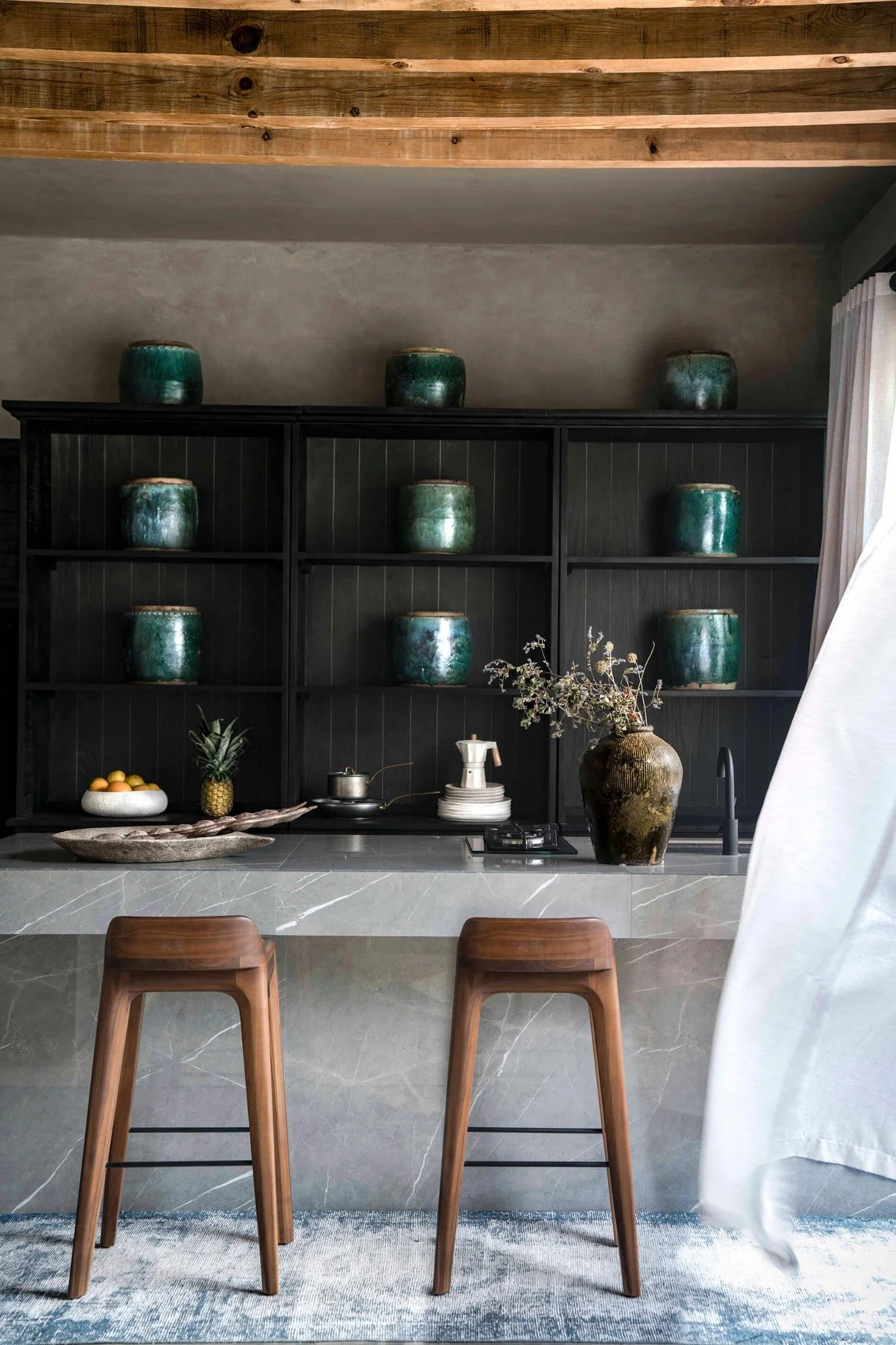 Minimal desert-inspired bedroom at Casa Etérea with kitchen shelving with green glazed pots  behind a marble island