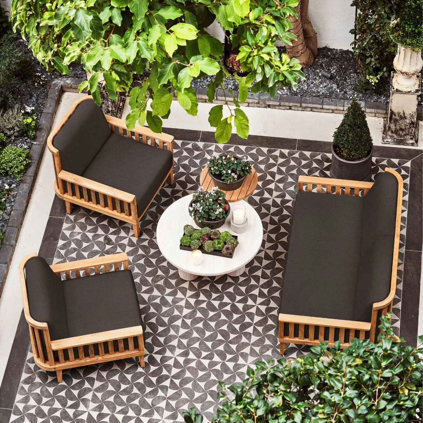 A set of teak and wooden outdoor furnature on black and white geometric tiles