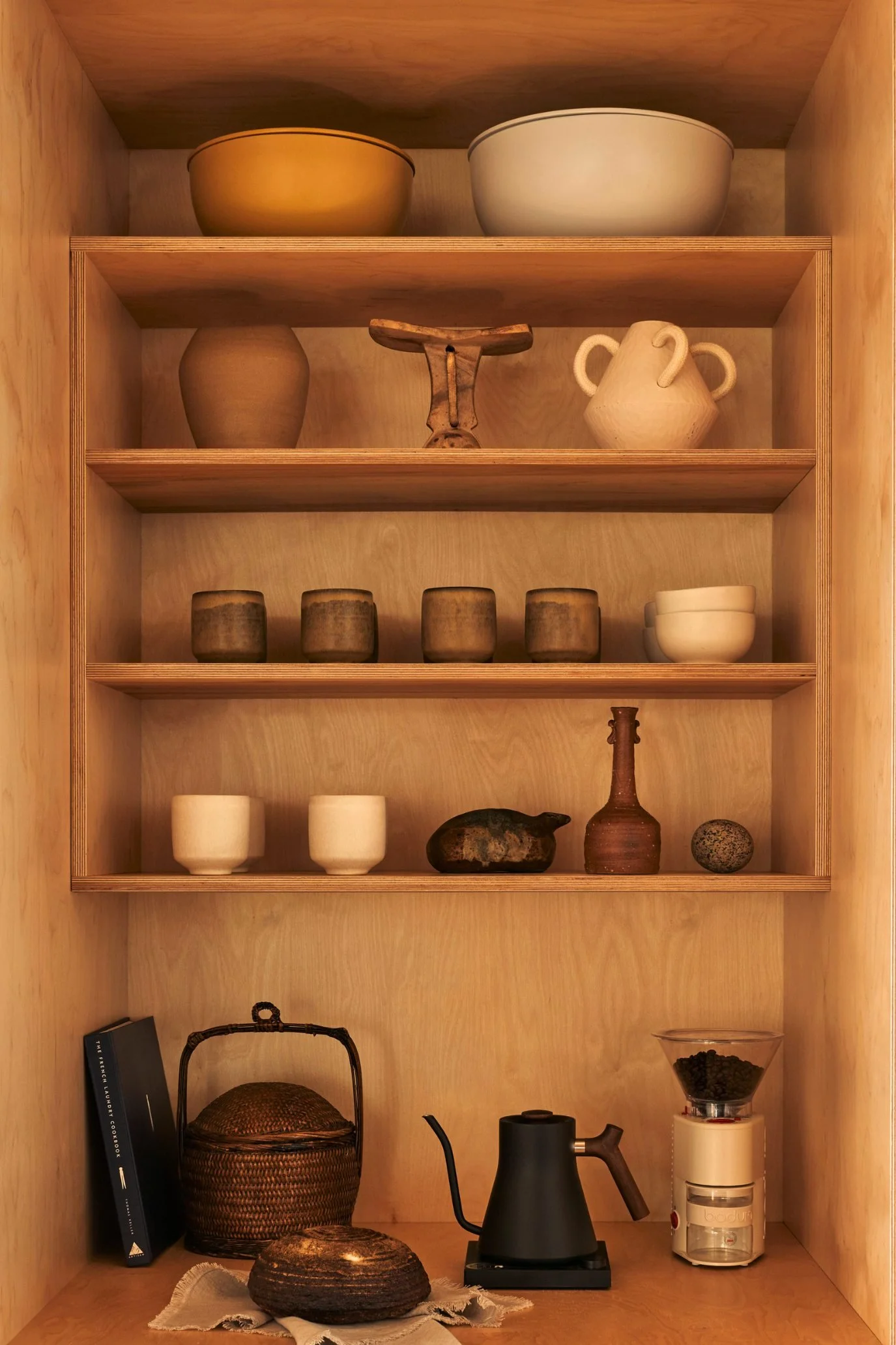 wooden shelving with rustic stoneware cups, vases and dishes