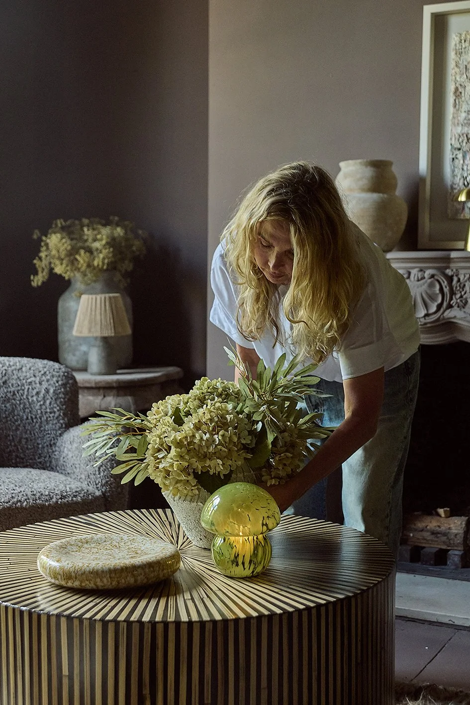Interior designer Abigail Ahern adding plants to a vase on a coffee table