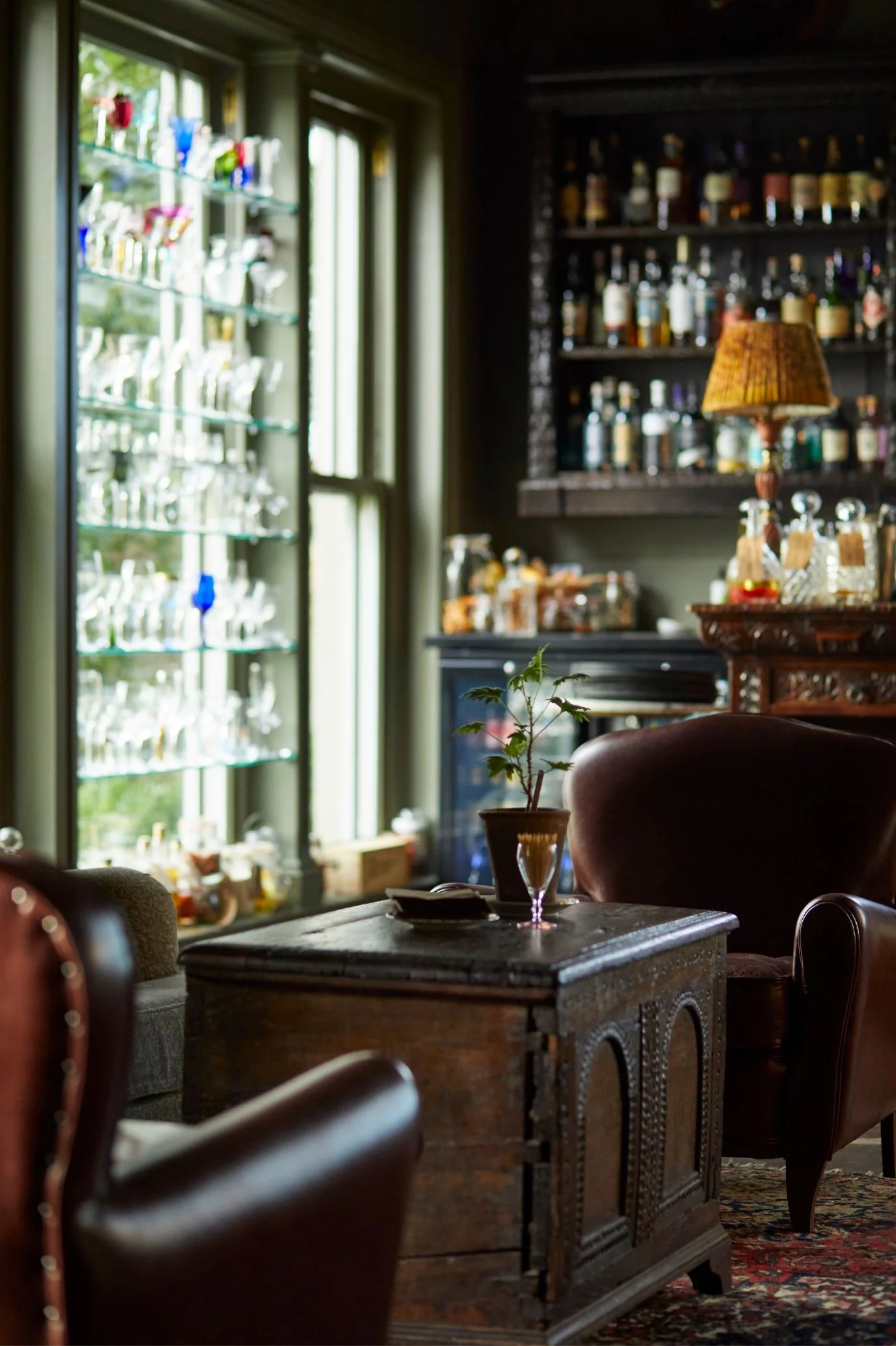 Vintage-style bar at The Pig hotel with dark cabinetry, leather seating and antique furniture