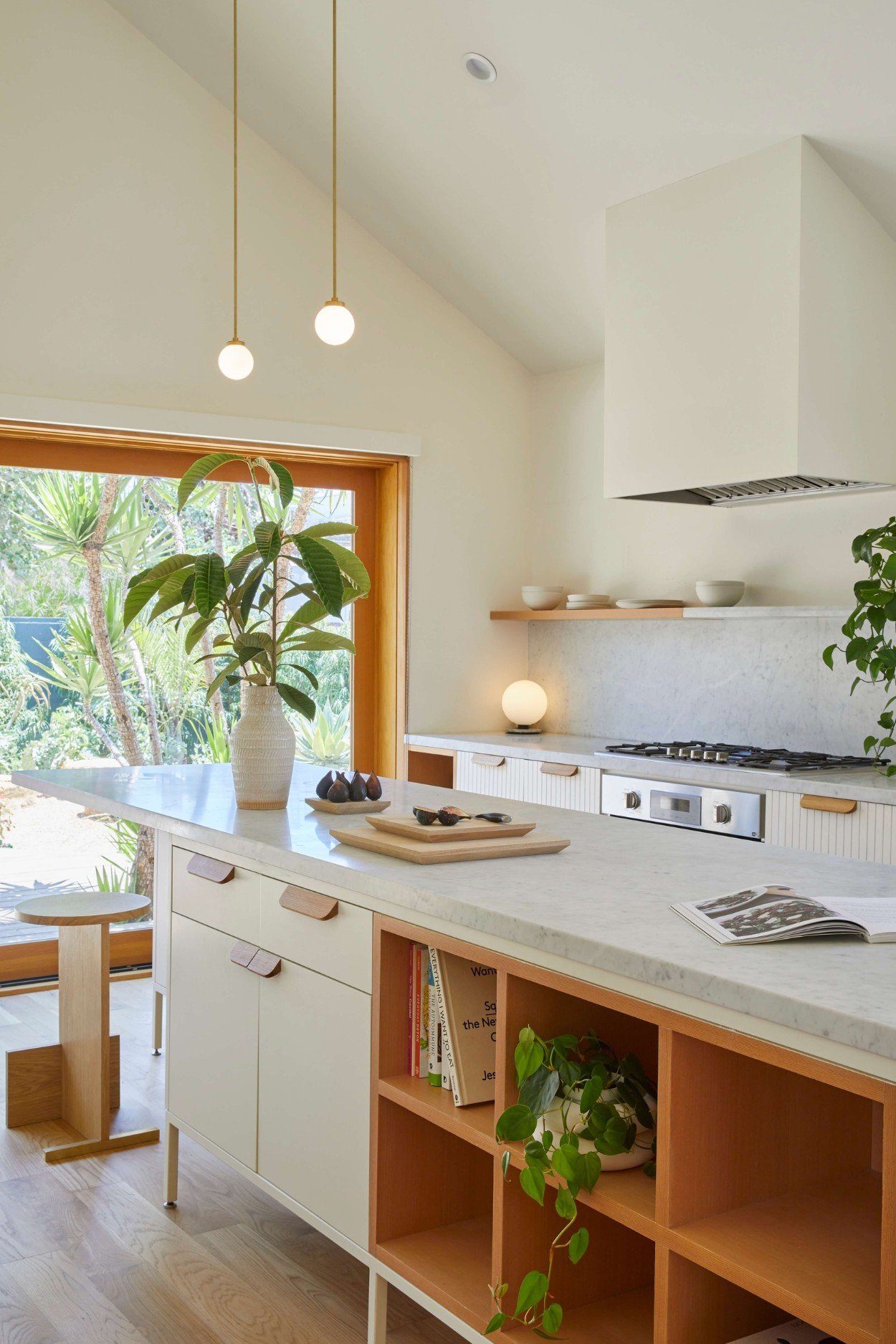 Modern kitchen with vaulted ceilings, marble worktops, wood-framed windows and mid-century lighting.