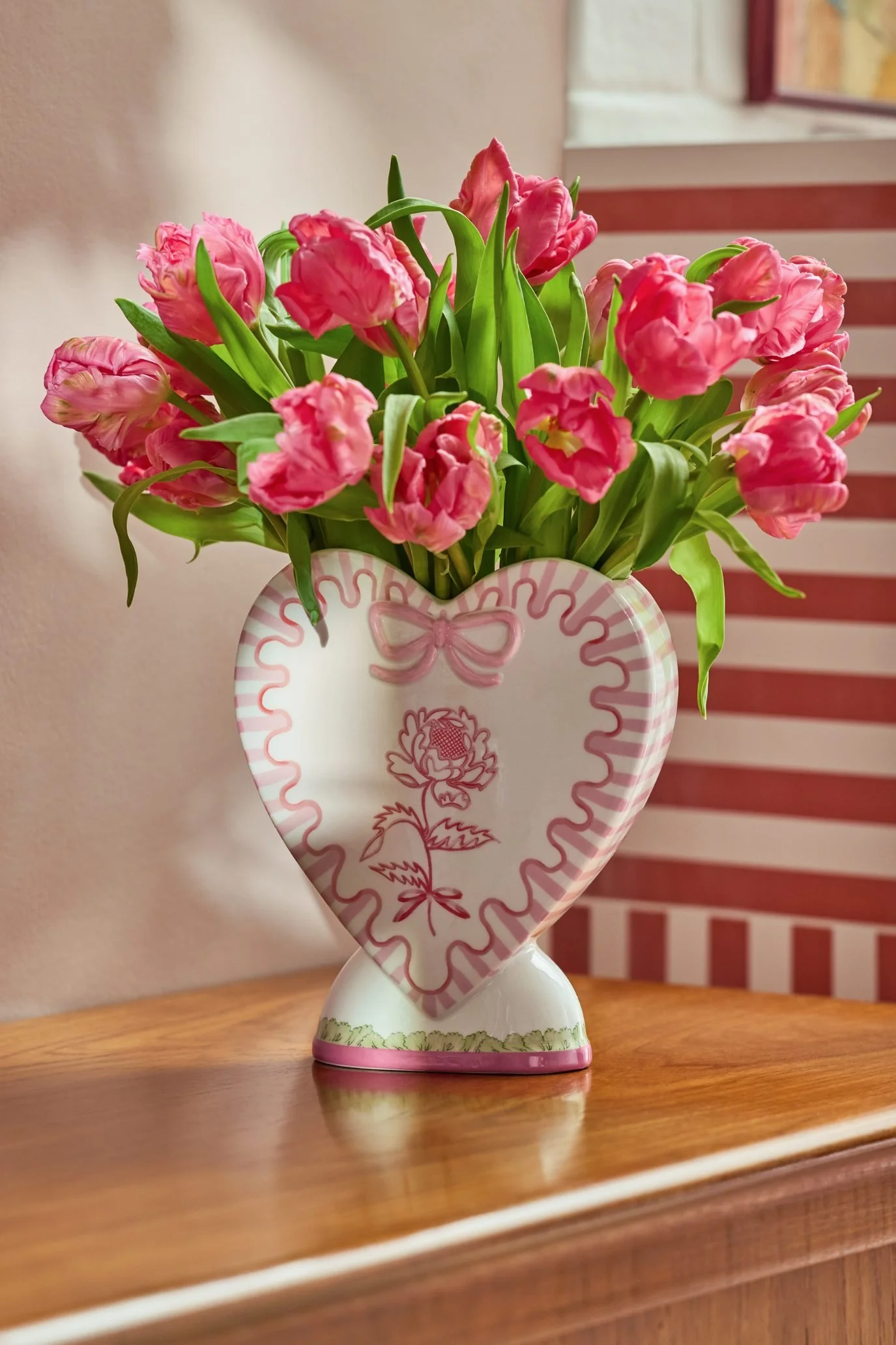Pink heart-shaped Cath Kidston vase filled with loosely arranged pink tulips.