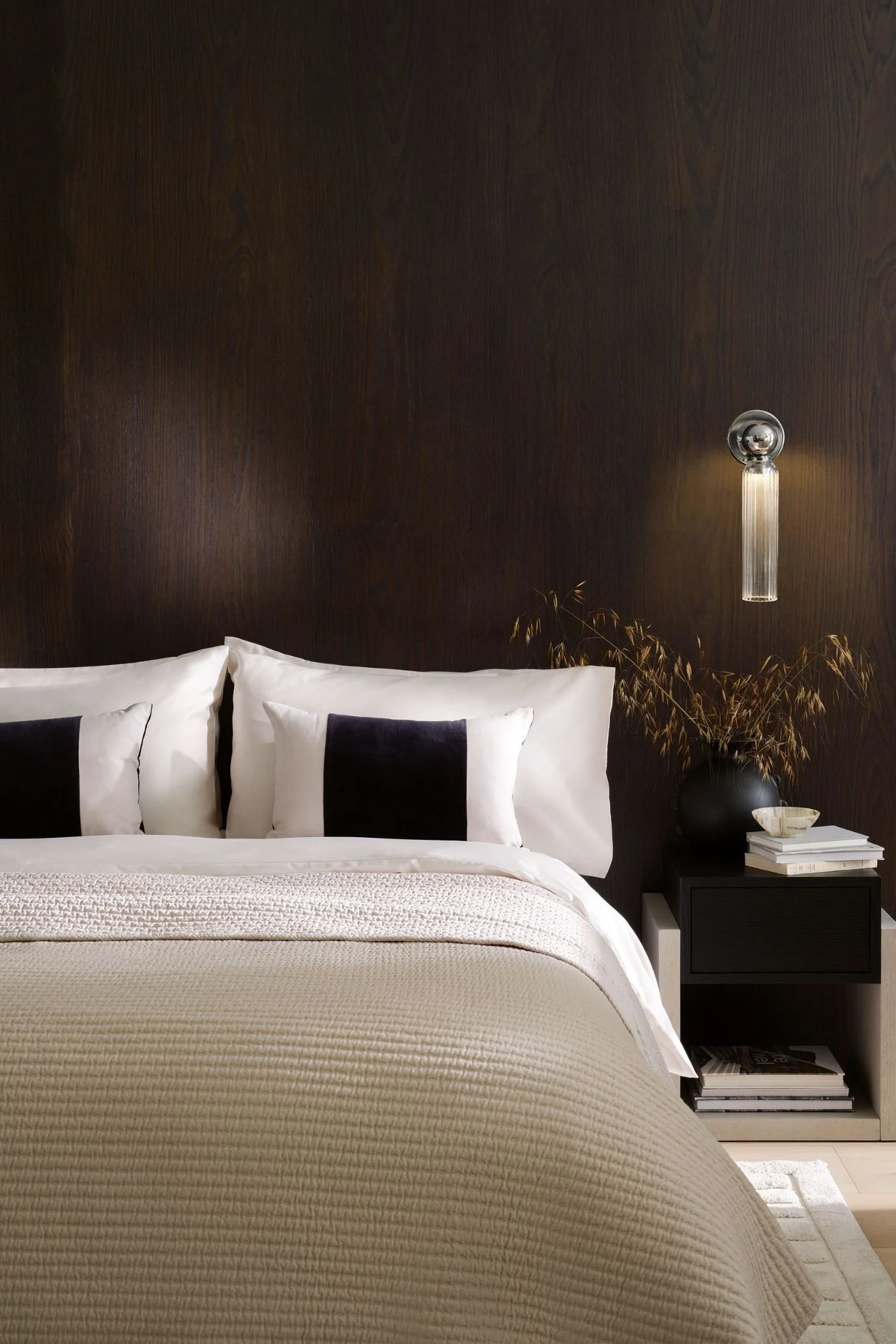 Kelly Hoppen x M&S white bedding with grey borders, layered cushions and a wood headboard.