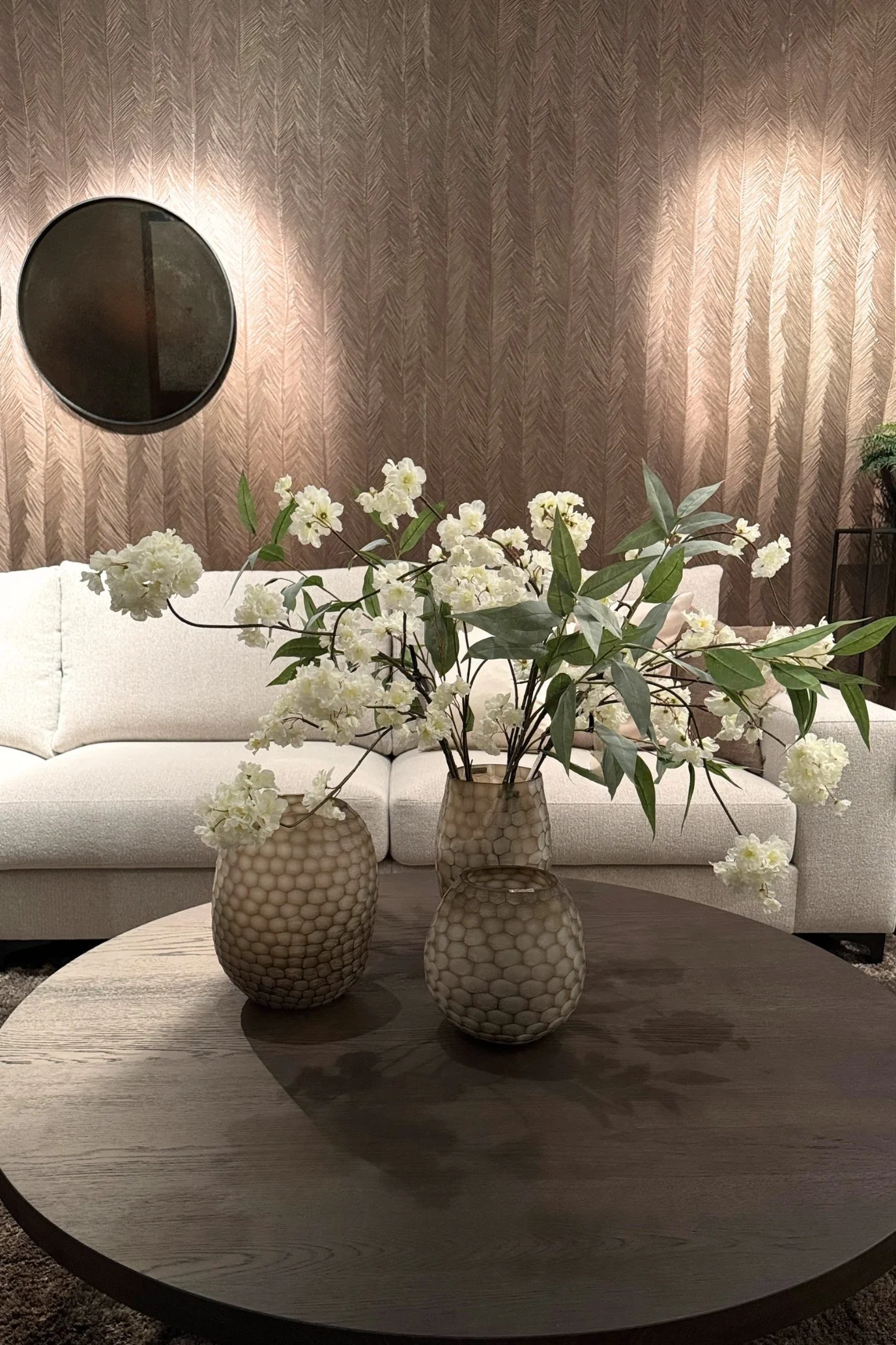 White faux blossom branches arranged in a decorative vase on a living room coffee table.