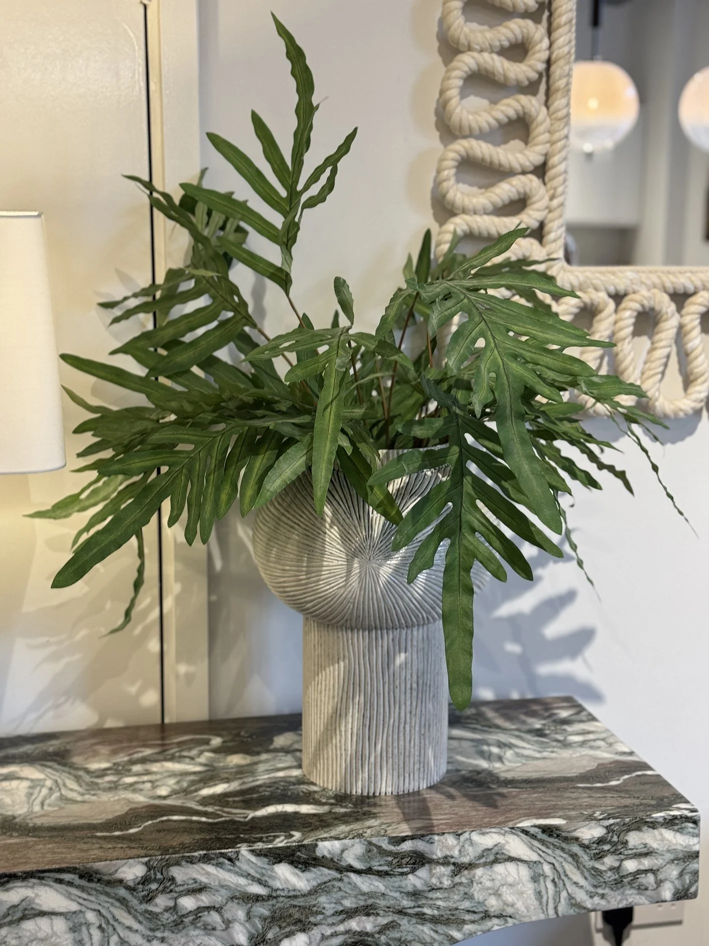 stylish plant in ribbed vase on a marble console table.