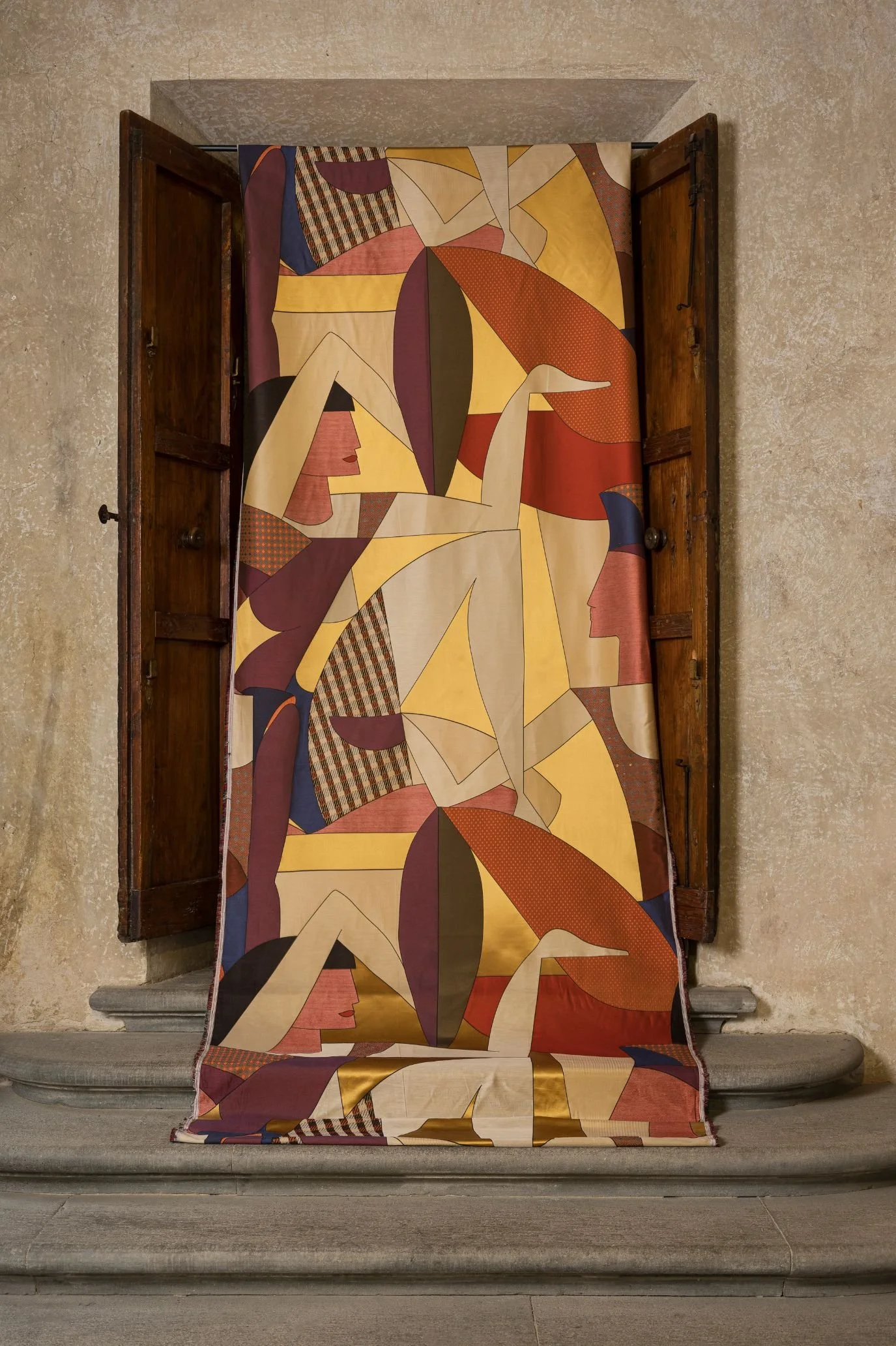 Colourful Alessandro Bini fabric with geometric shapes and stylised female profiles draped through an open window