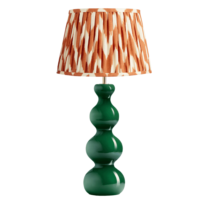 a table lamp with a green glass base and orange irate design shade