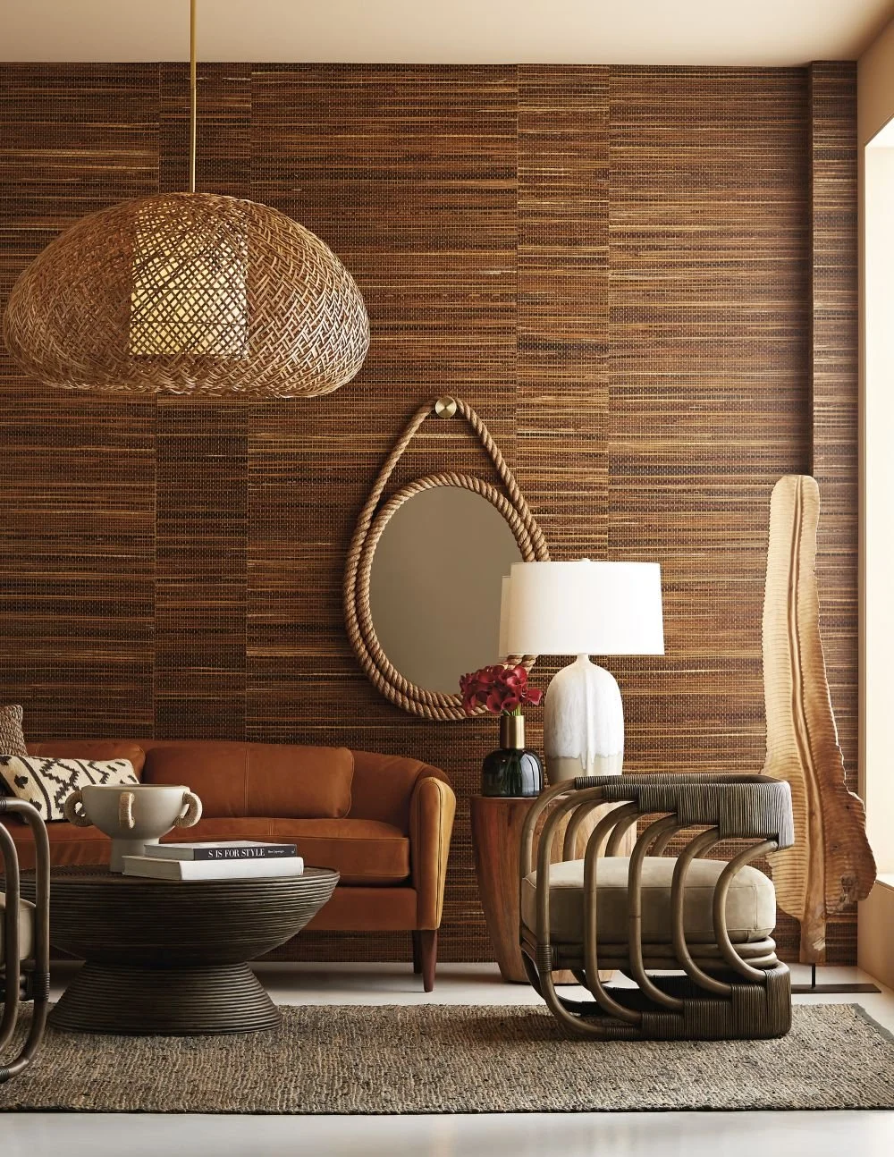 a room with brown woodlice wallpaper a large rattan pendant and an oval rope mirror on the wall
