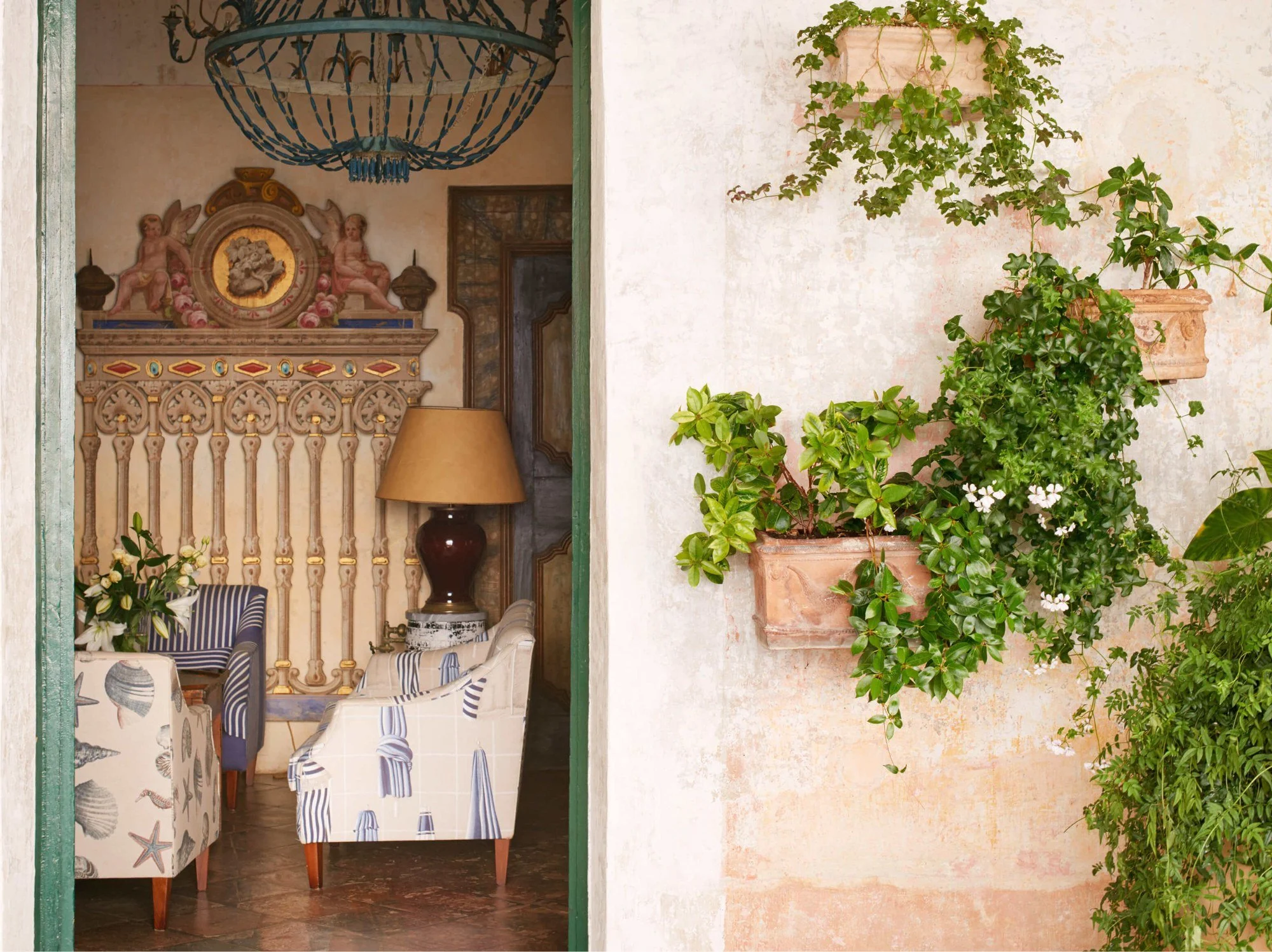 Elegant Amalfi Coast villa interior with Renaissance artwork, ornate chandeliers and coastal-inspired blue furnishings.