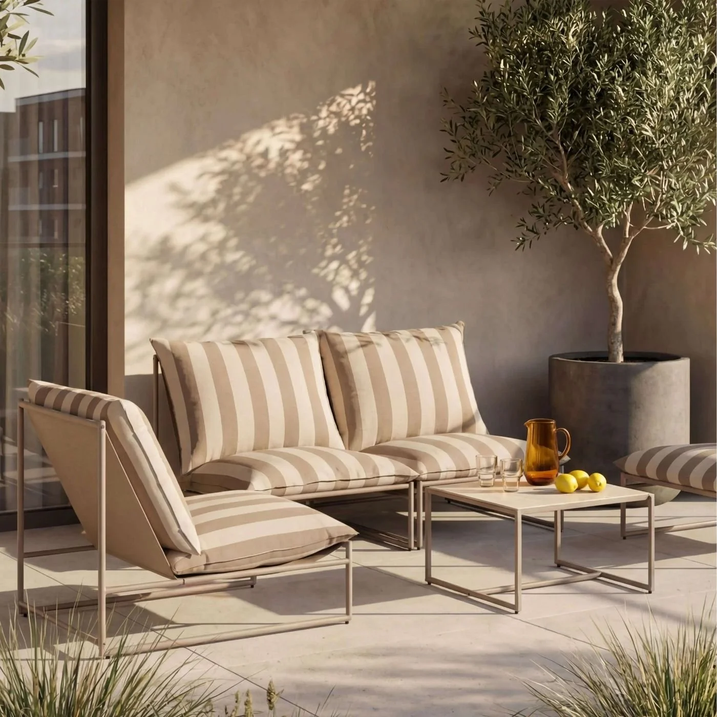 A stripy sofa and chair set on a terrace next to a large olive tree in a grey pot