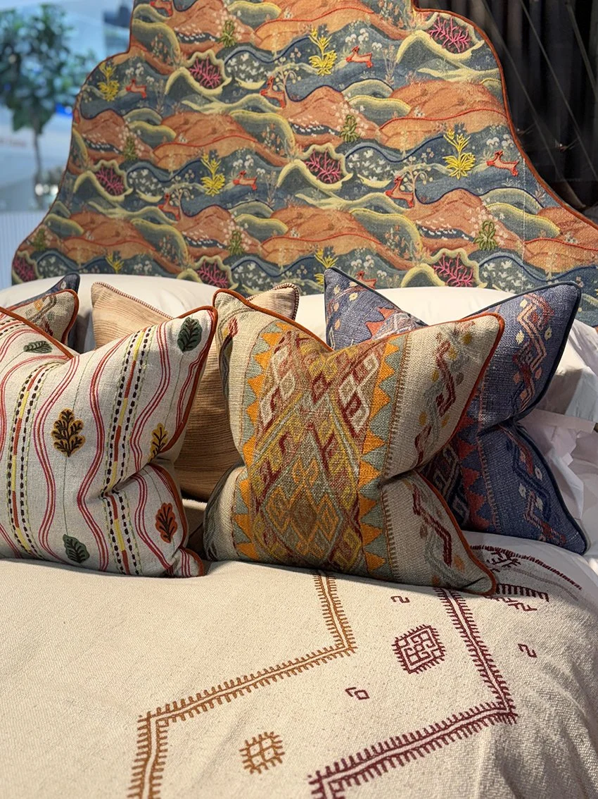 A bed with a patterned headboard and cushions in similar tones.