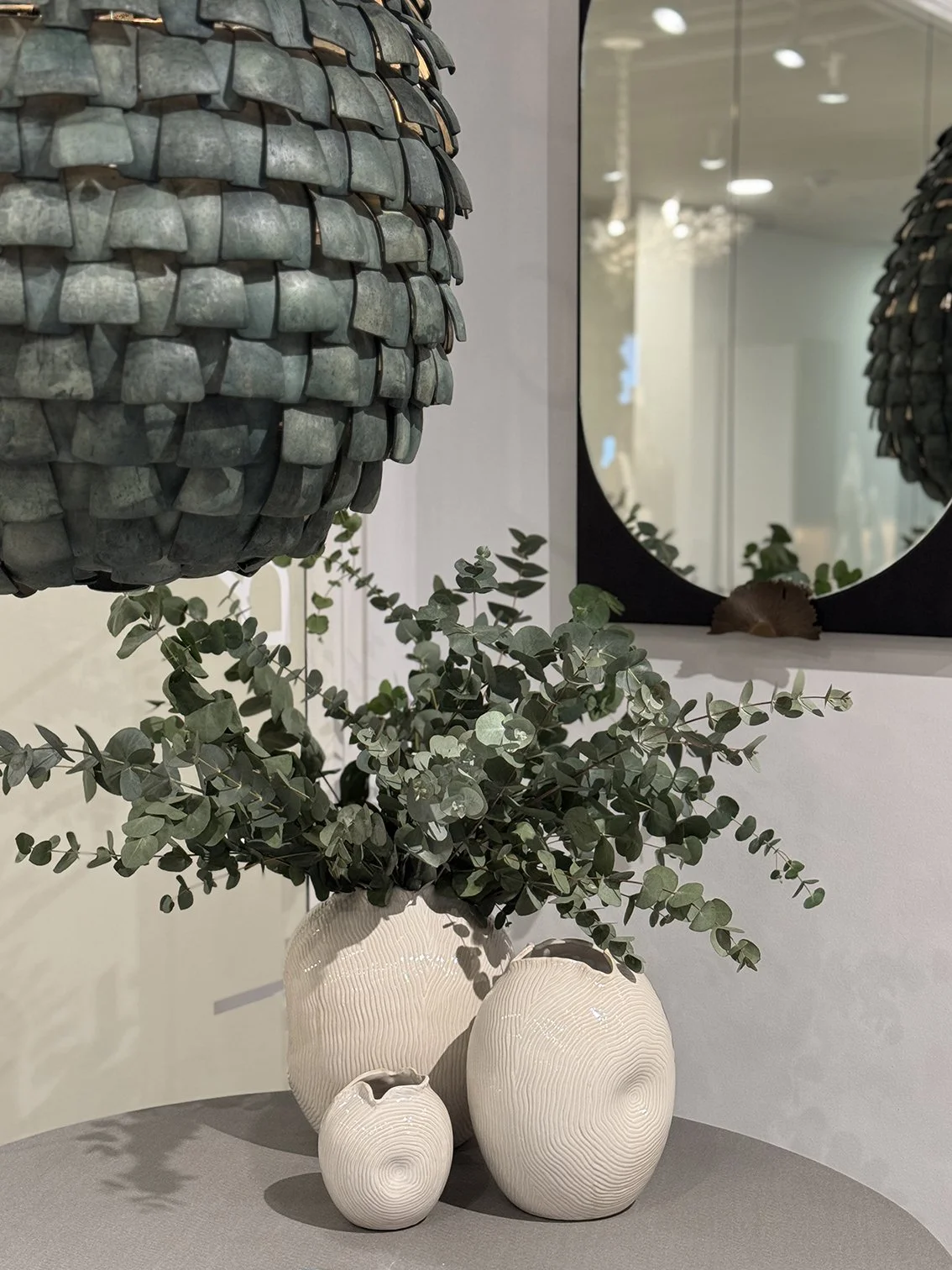 Dried leaves - eucalyptus in stylish white pots next tot a mirror and large metal pendant light