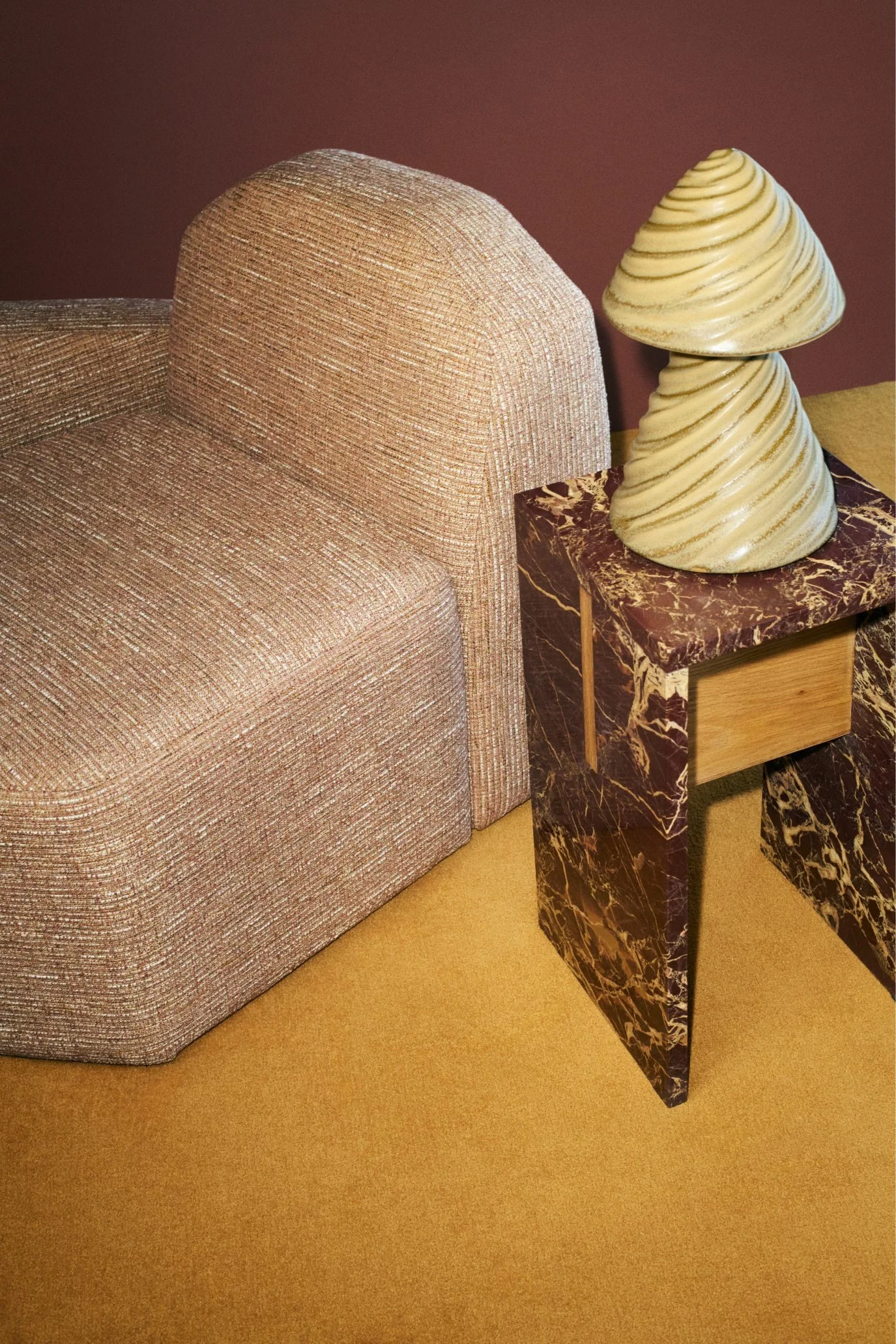 Upholstered lounge chair with burgundy marble side table and ceramic MORRA lamp from the Kelly Wearstler H&M HOME collection