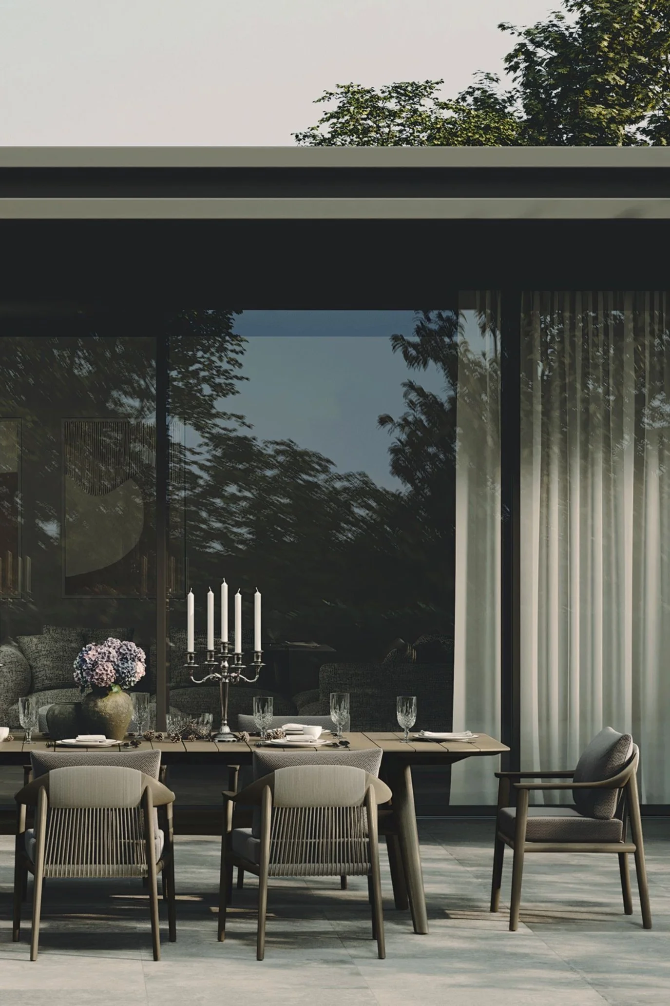 Elegant outdoor dining table set for dinner with a silver candelabra and flowers on a contemporary terrace.