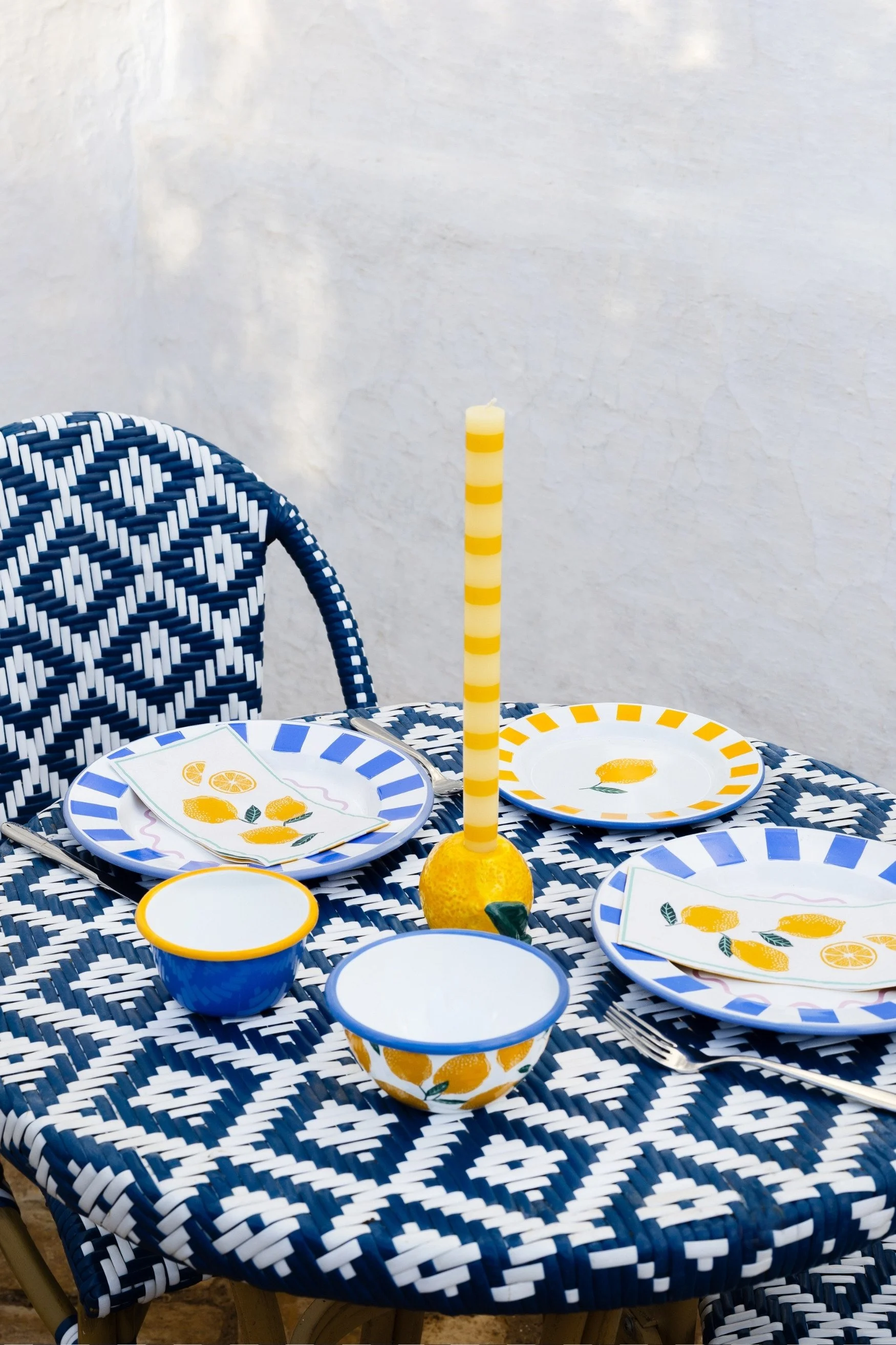 Blue and white cafe style table and chairs with blue, white and yellow plates on the table