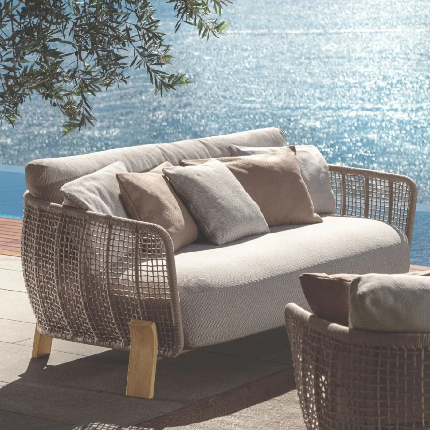 A luxurious rope curved outdoor sofa with accent cushions by the sea