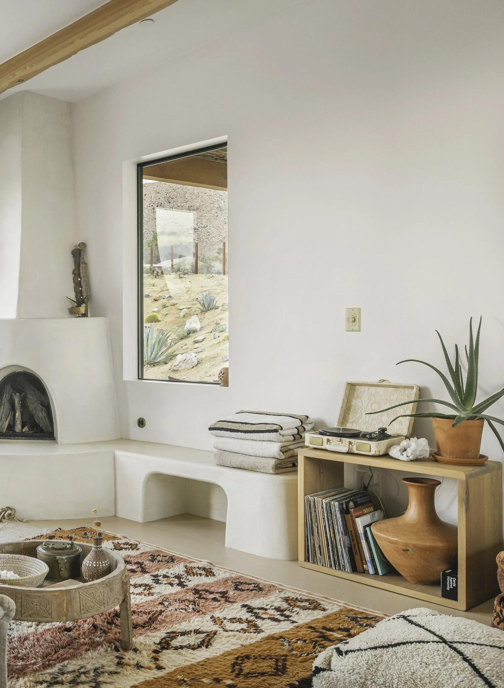 A record player sits on a wooden unit and a Moroccan rug adds pattern in earthy tones, while pottery from local artisans and woven accents