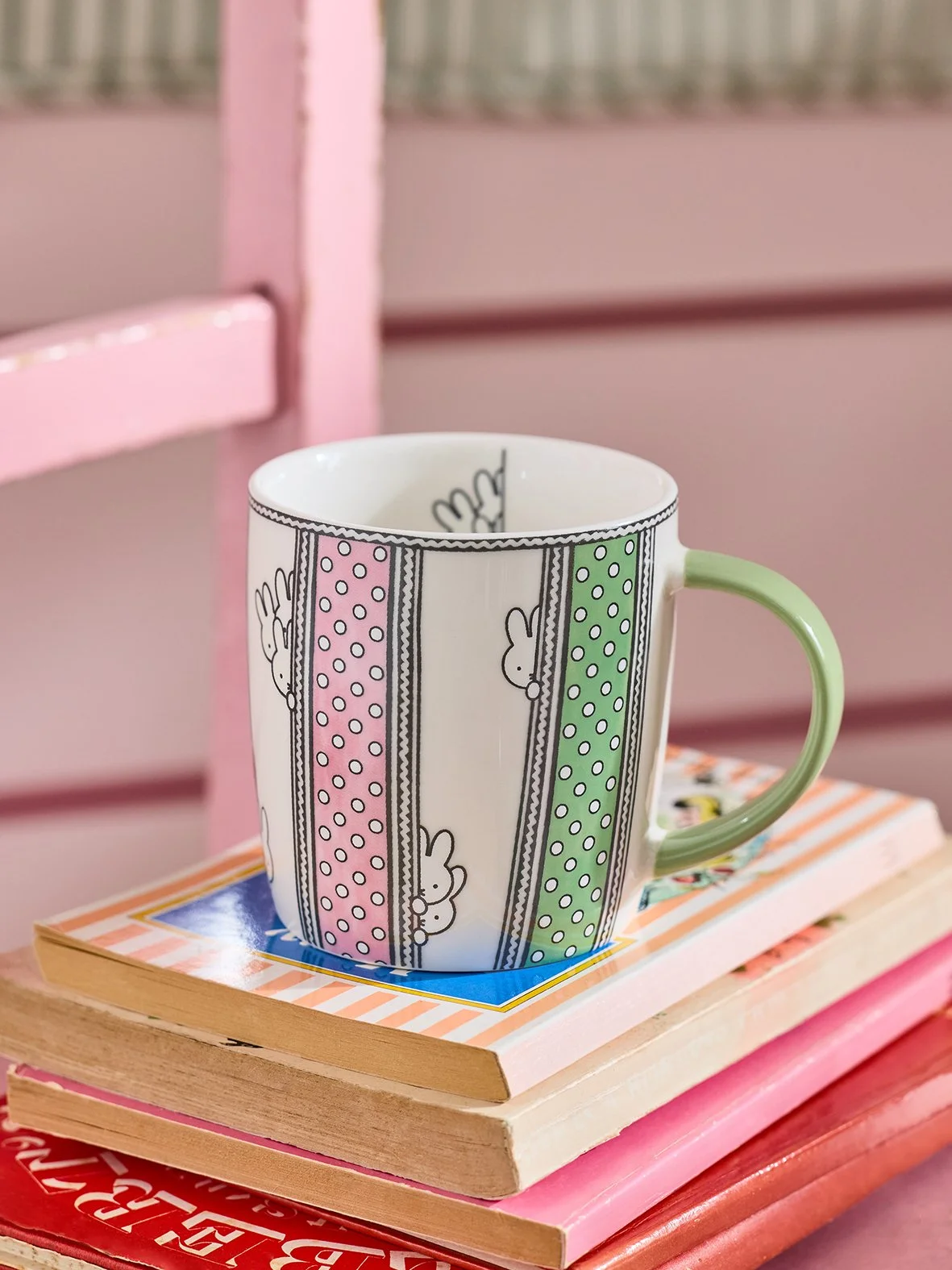 A cup with green and pink pattern with Miffy the rabbit illustrations