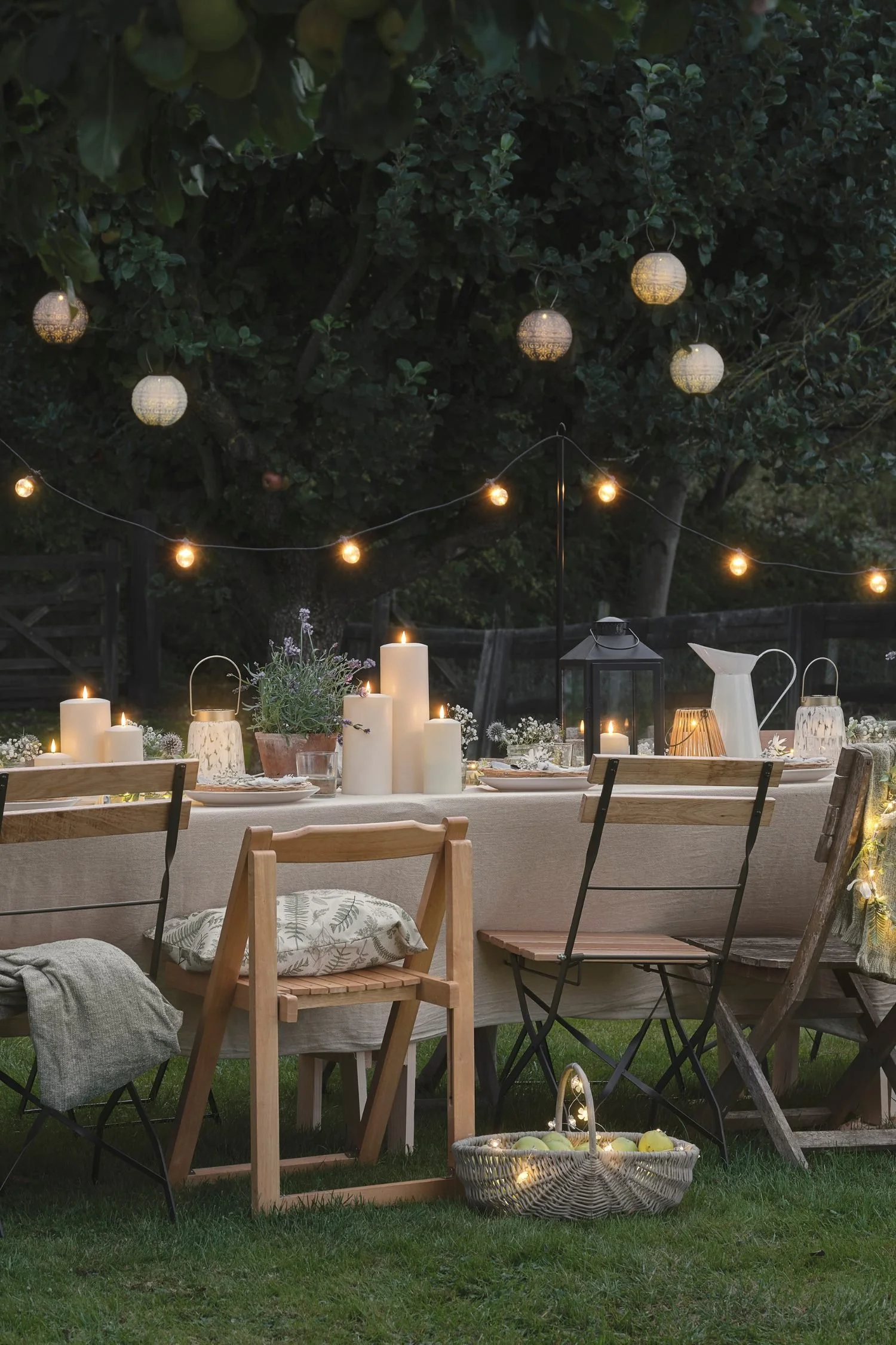 Outdoor lighting ideas with festoon lights, lanterns and LED candles creating a magical alfresco dining setting.